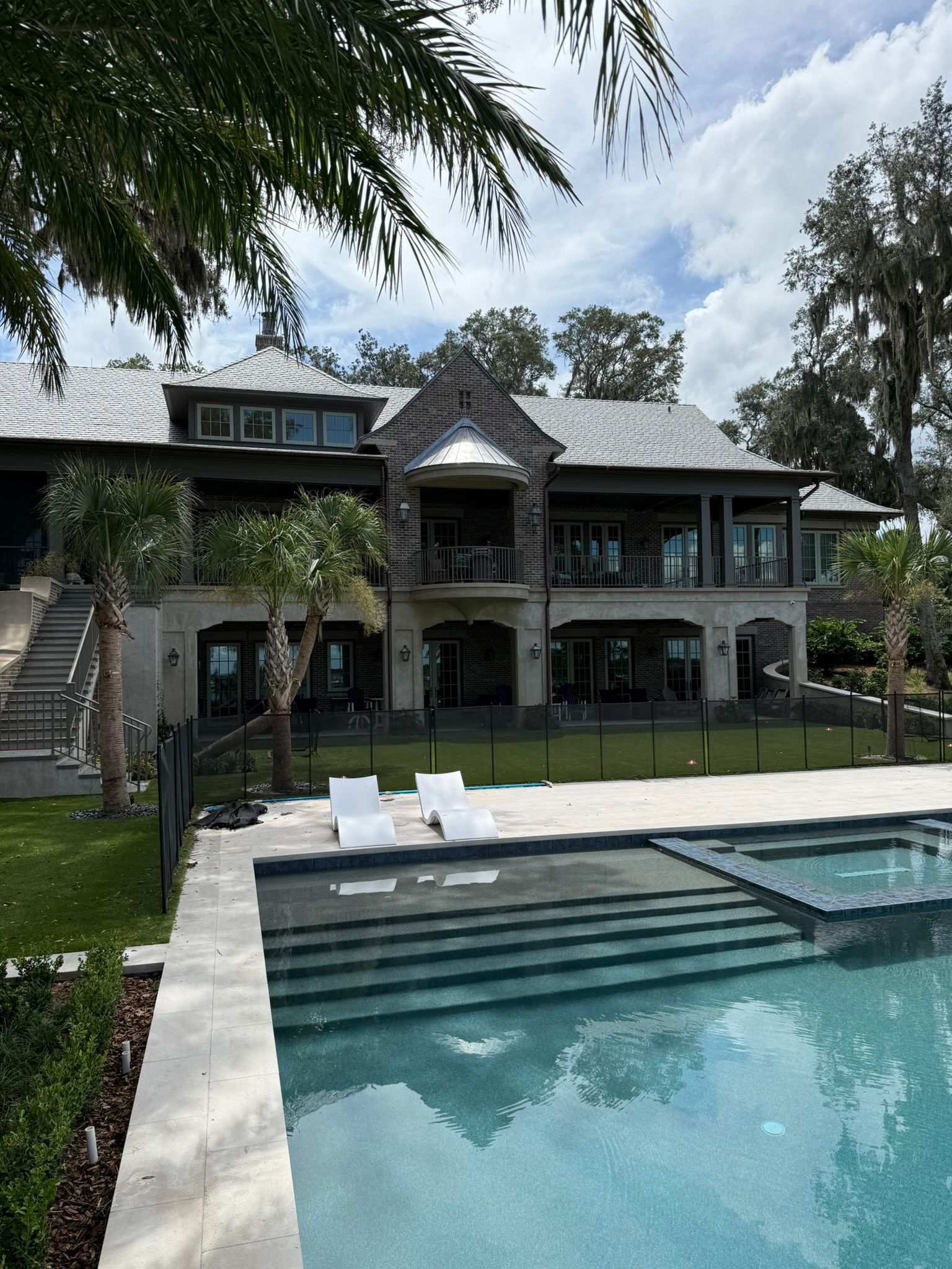 Luxury house with pool and lounge chairs in a tropical backyard
