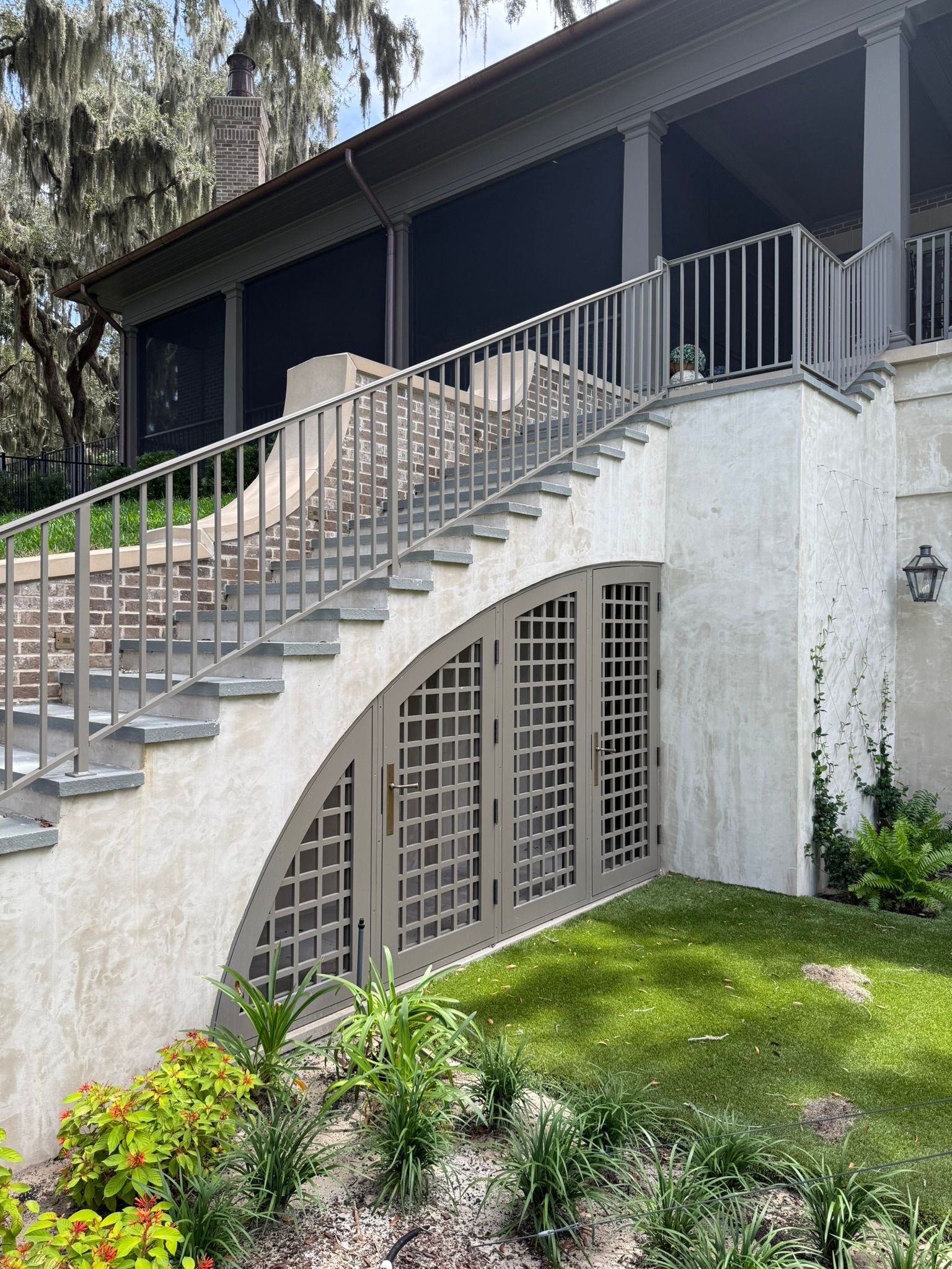 Exterior staircase with metal railings leading to a house above a grassy, landscaped slope