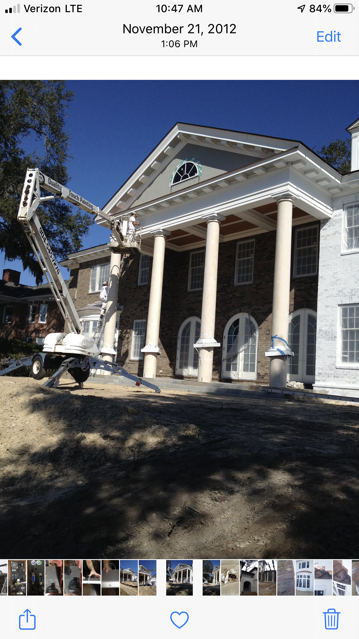 House with columns; lift extending toward roof, construction or maintenance activity.