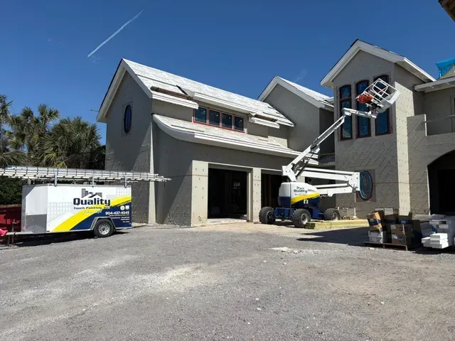Construction site: crew working on a two-story building.  Boom lift extends to windows. A trailer with the 