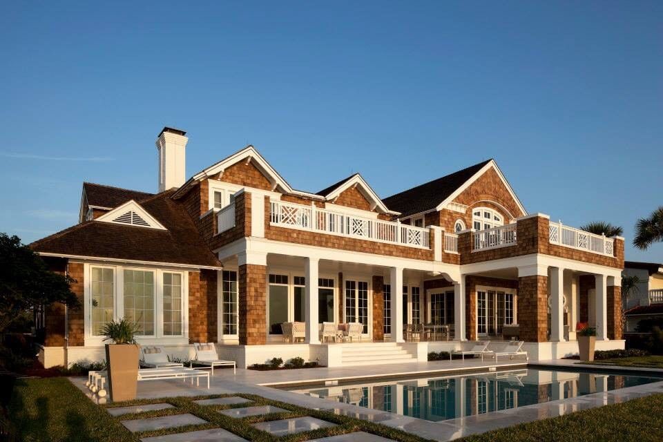 Luxurious house with a pool and waterfront patio under a clear blue sky