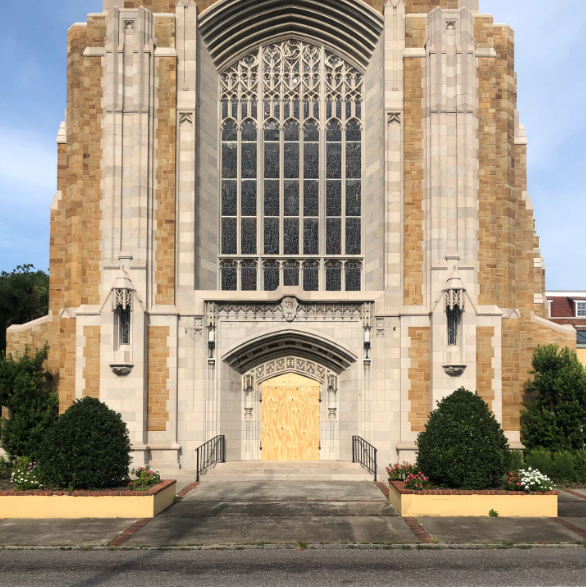Gothic stone church facade with tall arched windows and ornate yellow doors