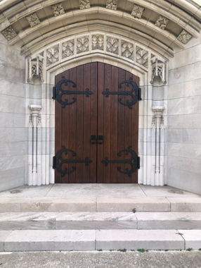 Wooden arched church door with ornate stone surround and steps leading up to it