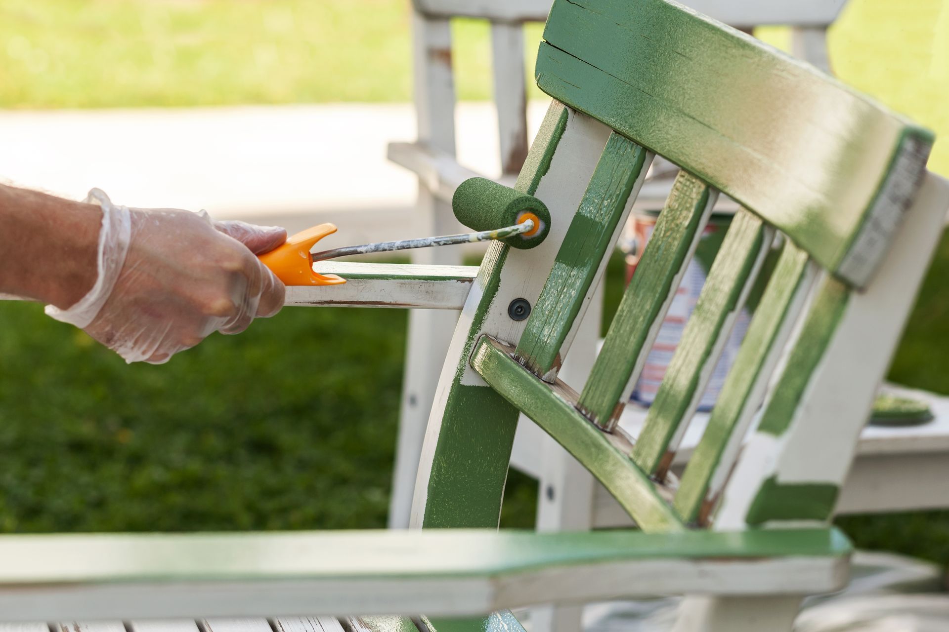 A person is painting a chair with a roller and scissors.