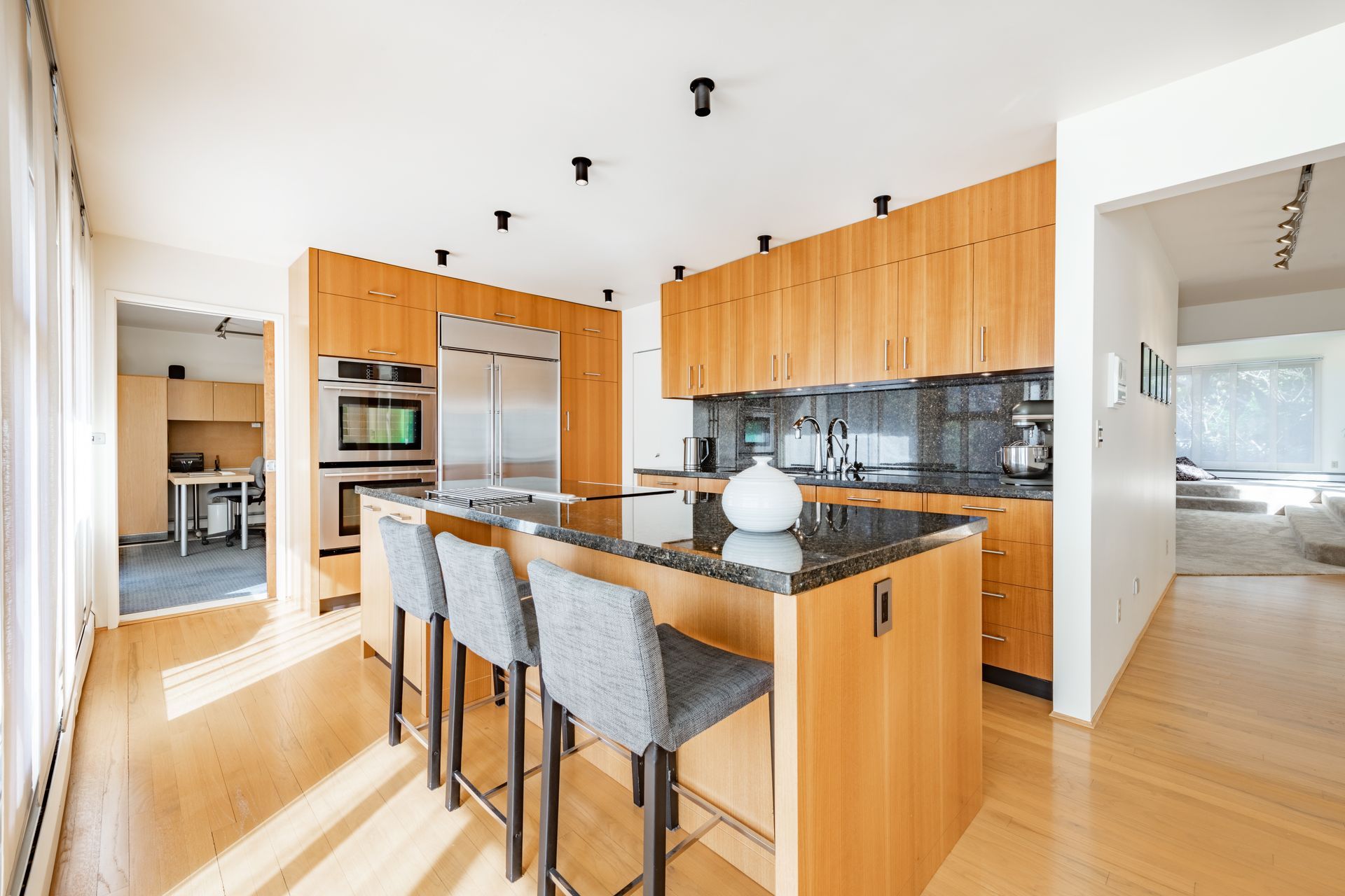 Modern kitchen with wood cabinets, granite island, and bar stools.
