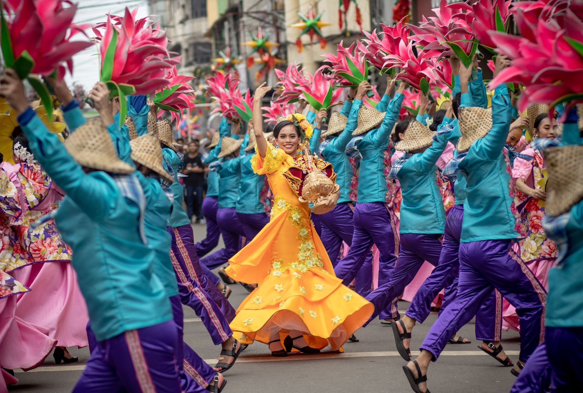 Colorful street dancers in teal and purple perform around a central dancer in a bright yellow dress.