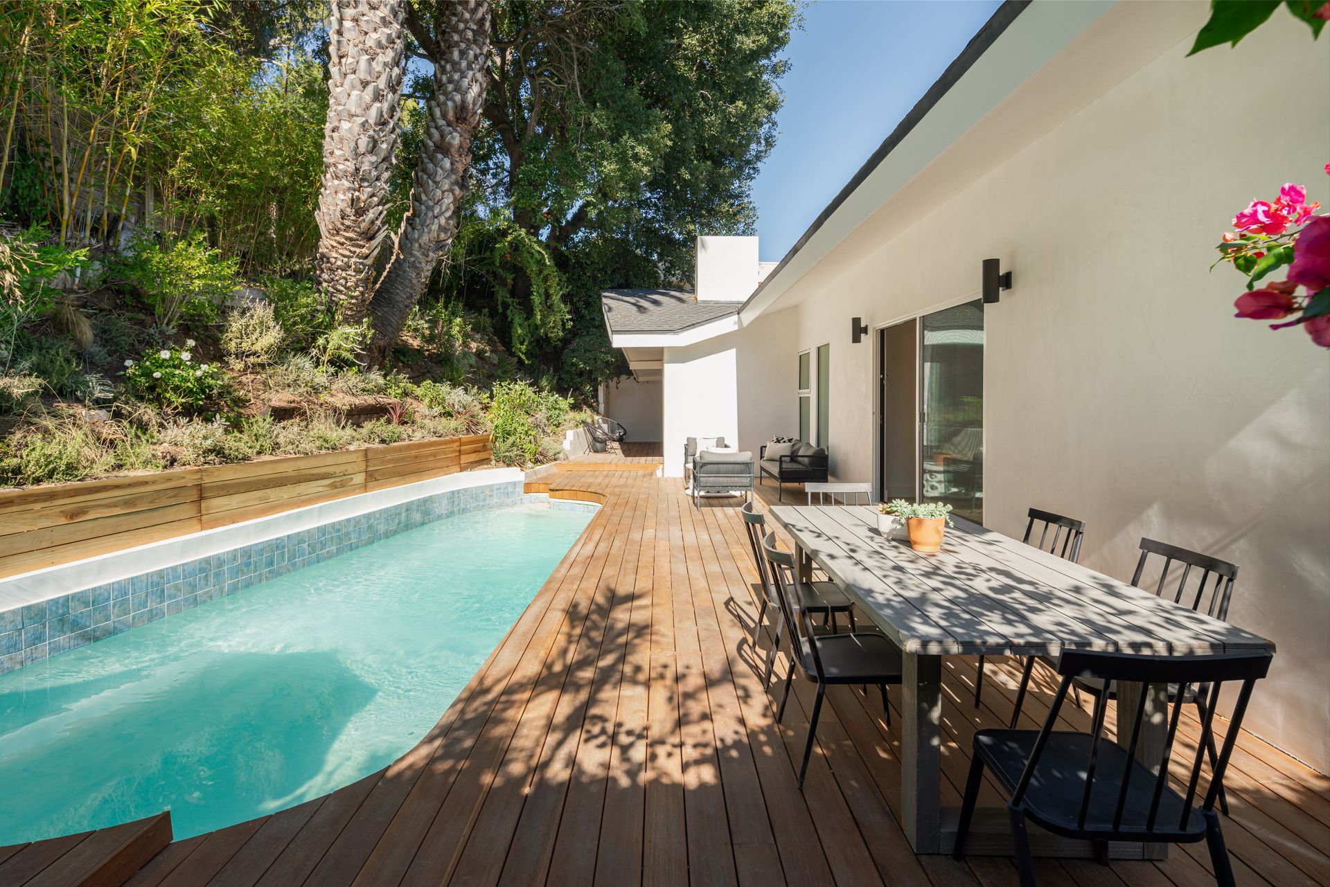 There is a large swimming pool in the backyard of a house.