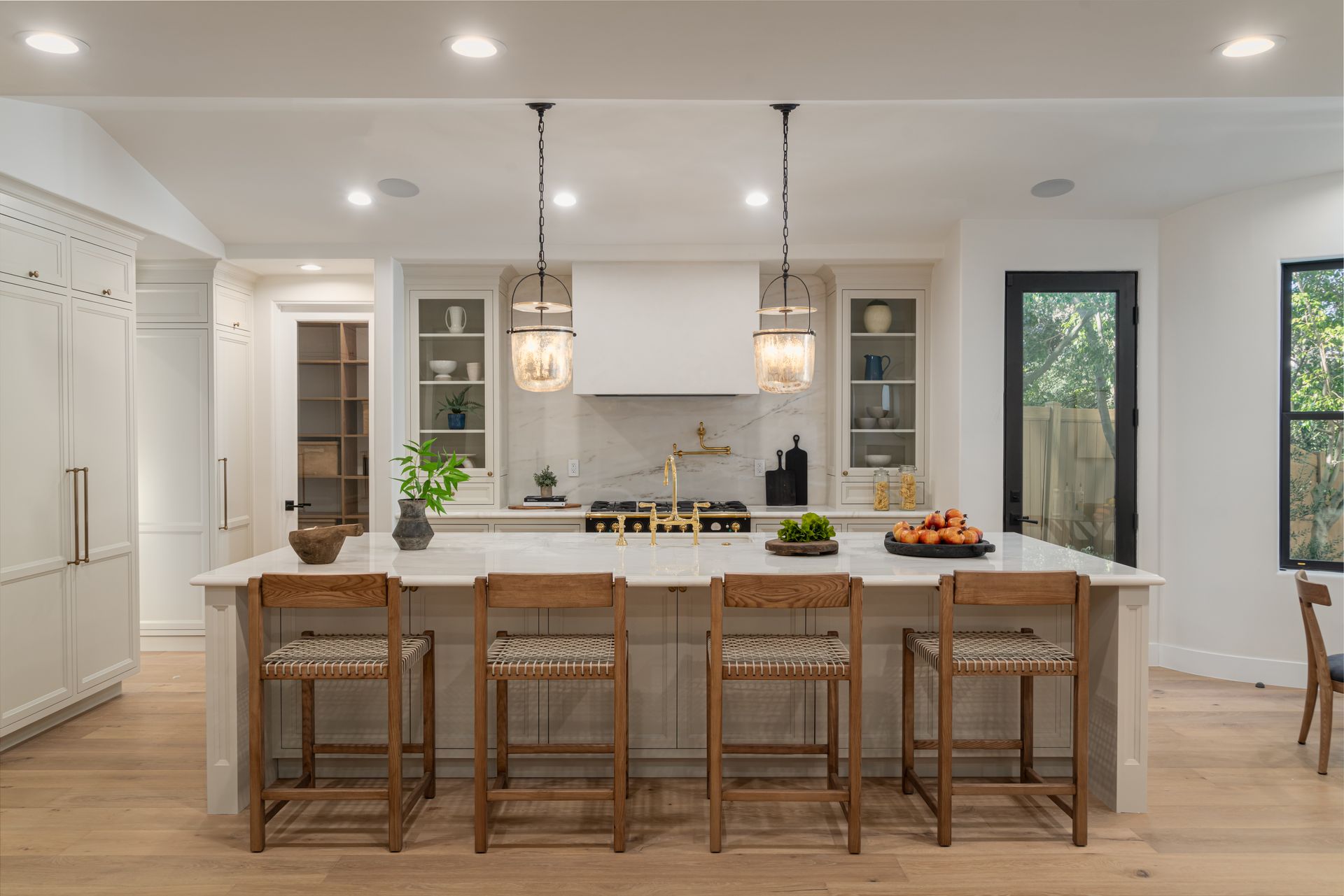 A kitchen with a large island , stools and a stove.