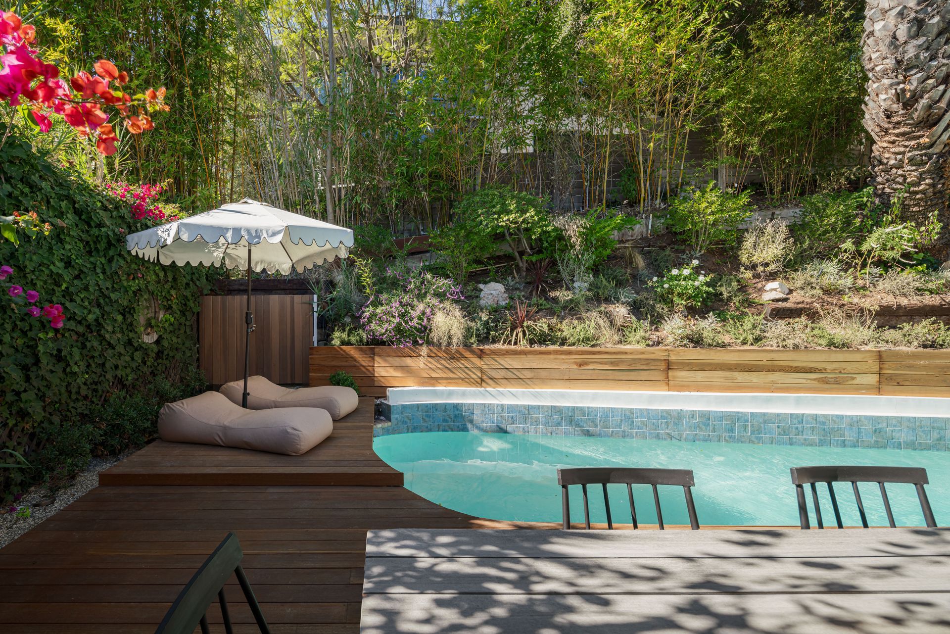There is a swimming pool in the backyard with a table and chairs.