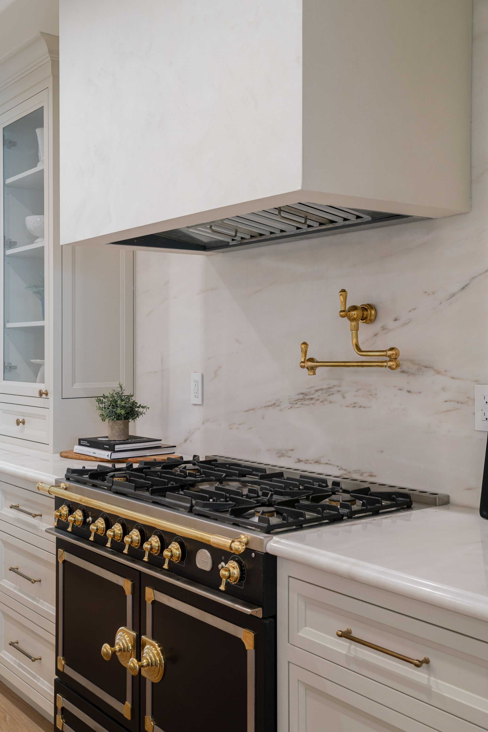 A black and gold stove in a kitchen with white cabinets.