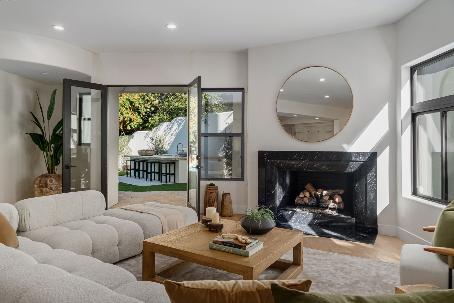 A living room with a fireplace , couch , coffee table and mirror.