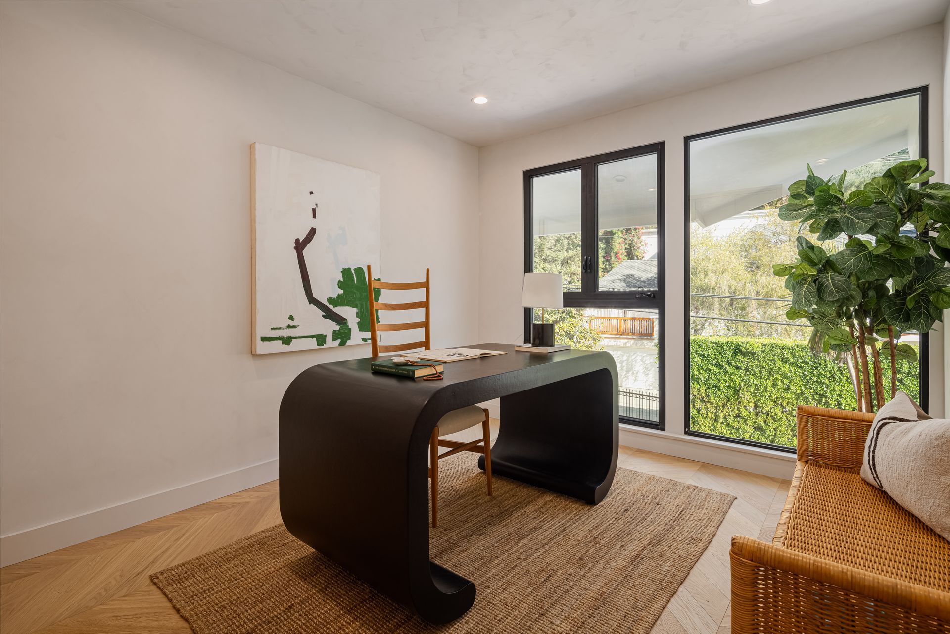 A home office with a desk and chairs and a large window.