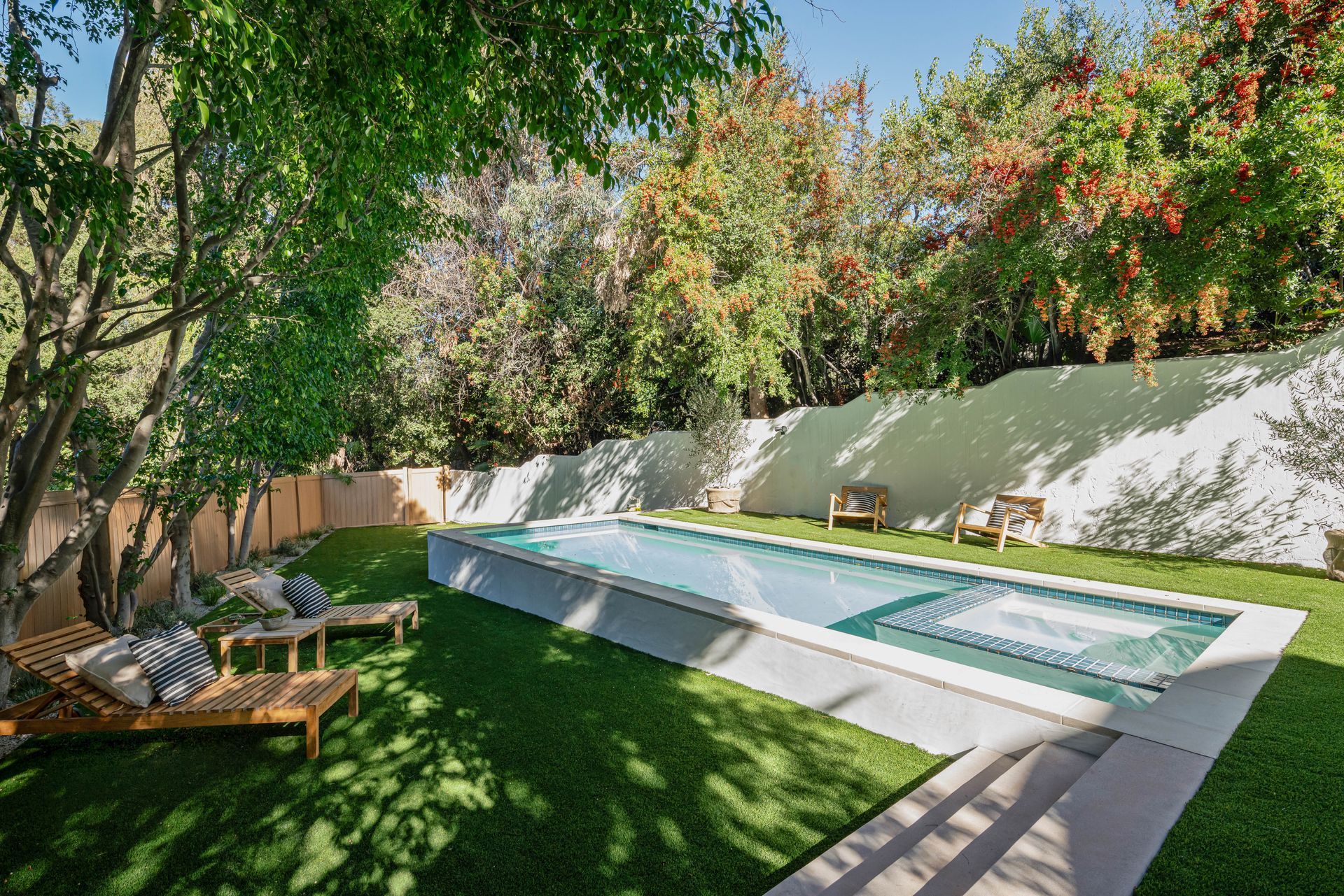 A large swimming pool in a backyard surrounded by trees and chairs.