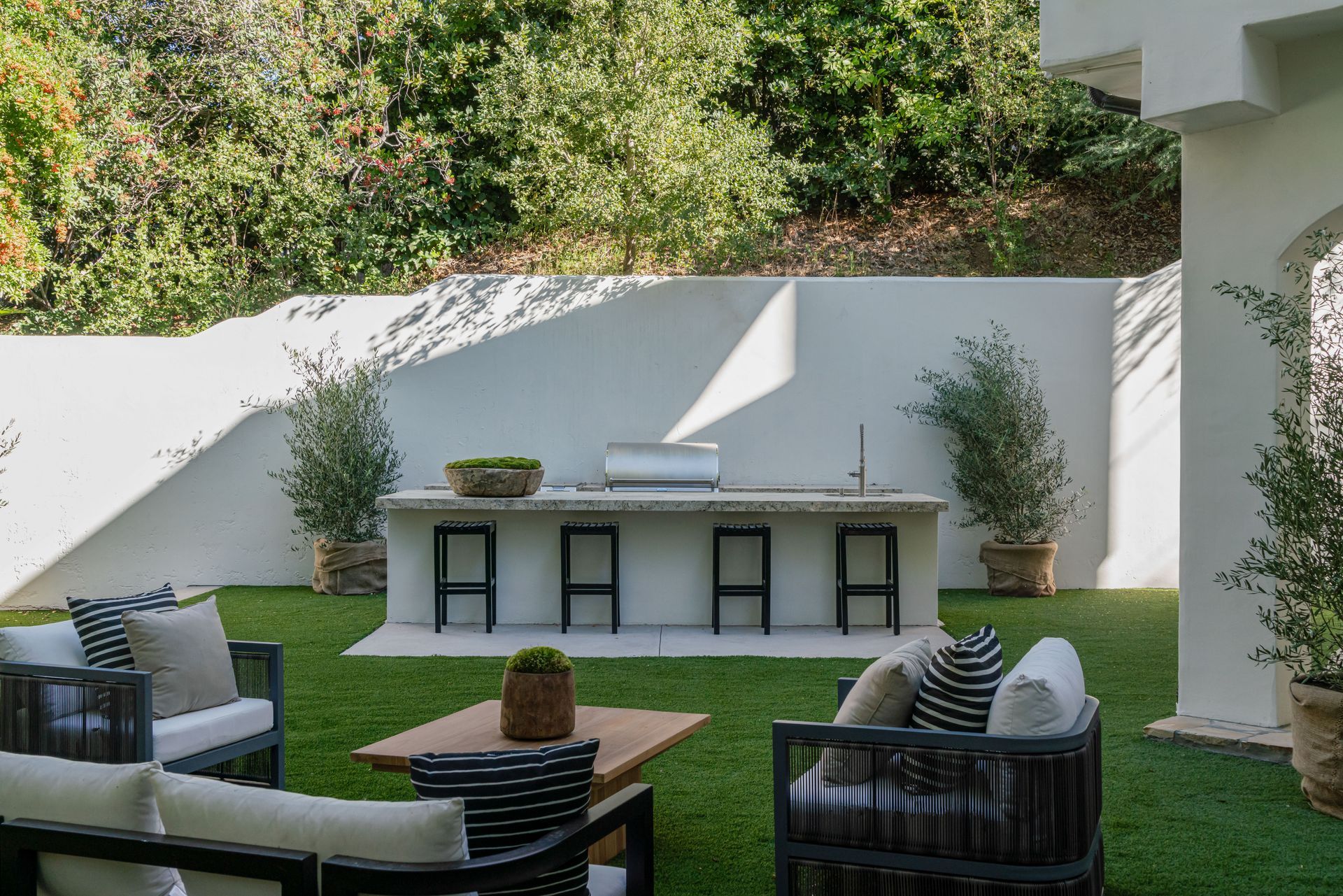 A patio with a couch , chairs , table and grill.
