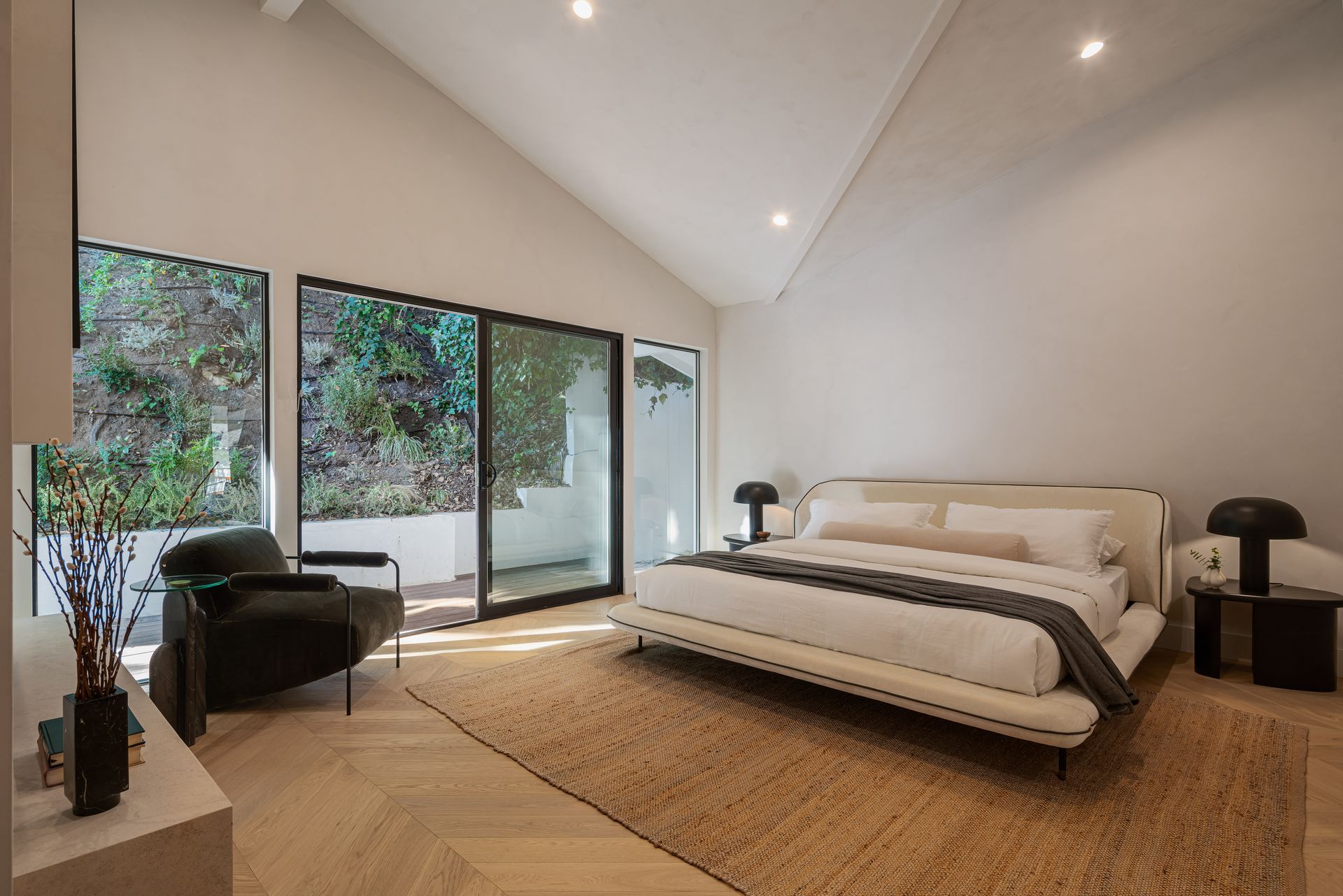 A bedroom with a large bed , chair and sliding glass doors.