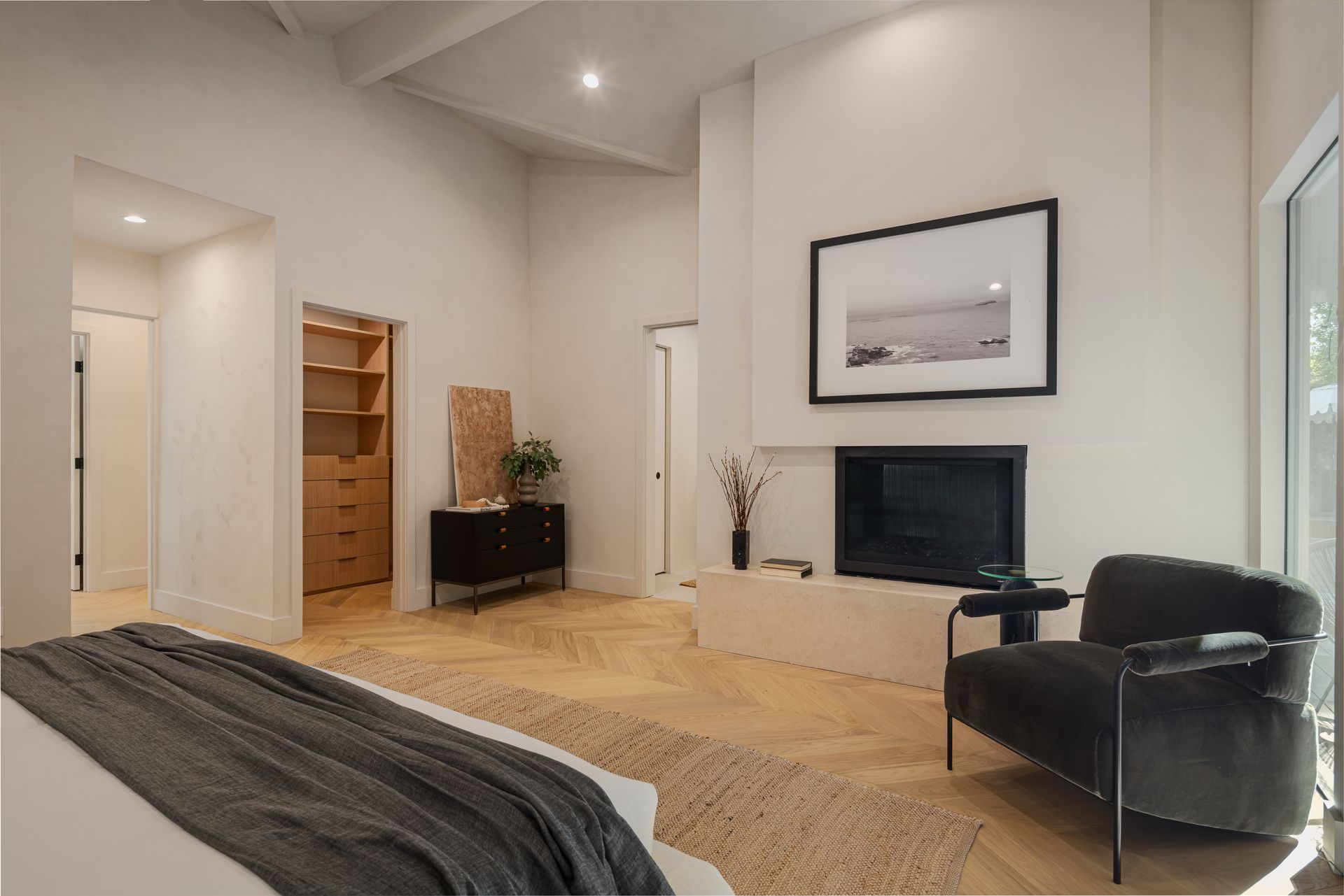 A bedroom with a bed , chair and fireplace.