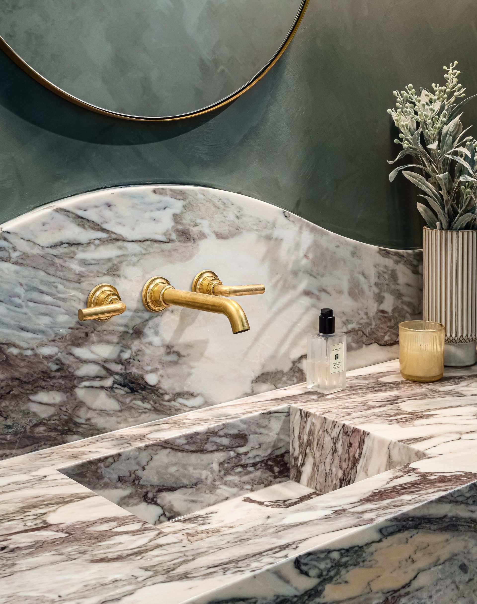 A bathroom sink with a marble counter top and gold faucets