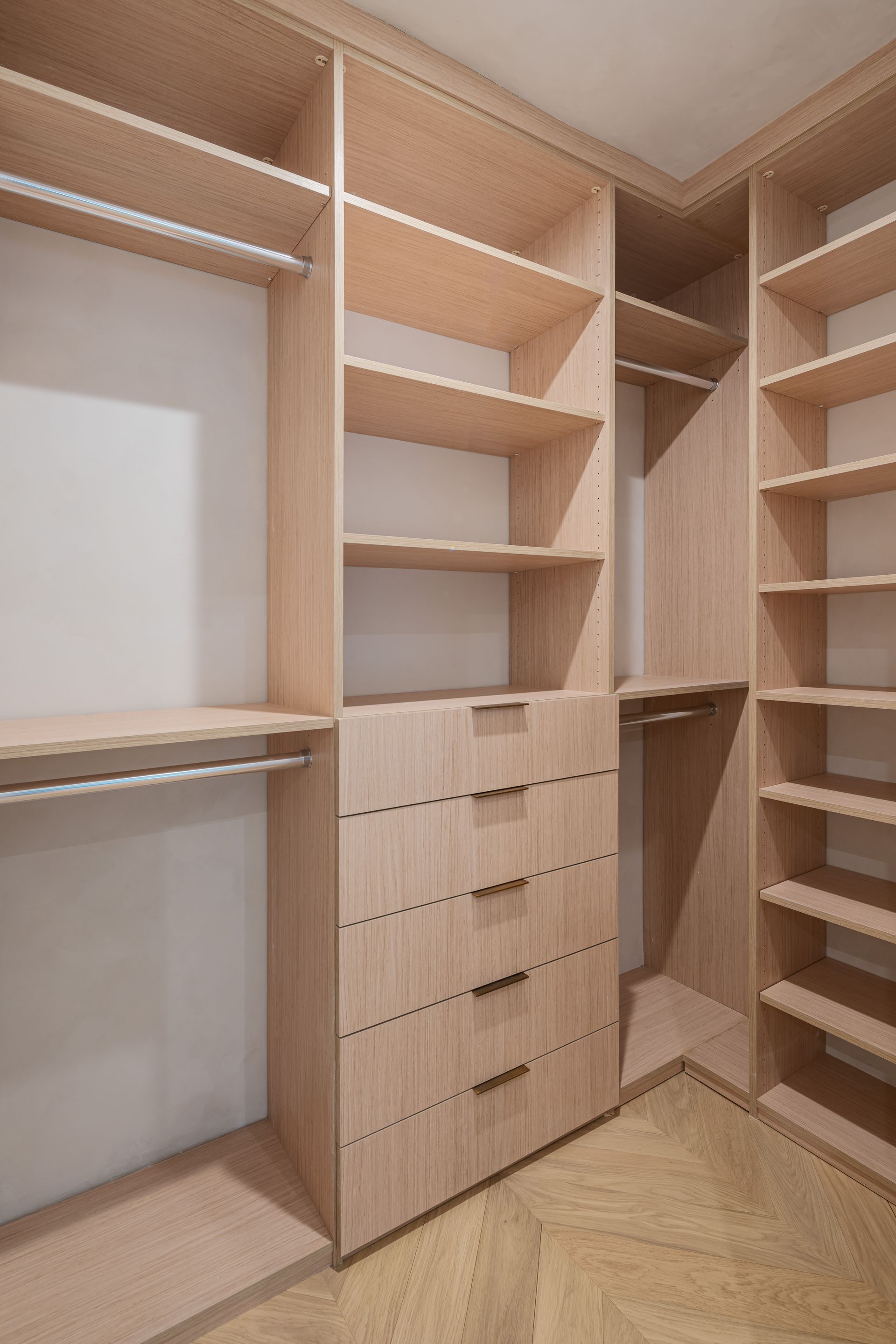 A walk in closet with lots of shelves and drawers.