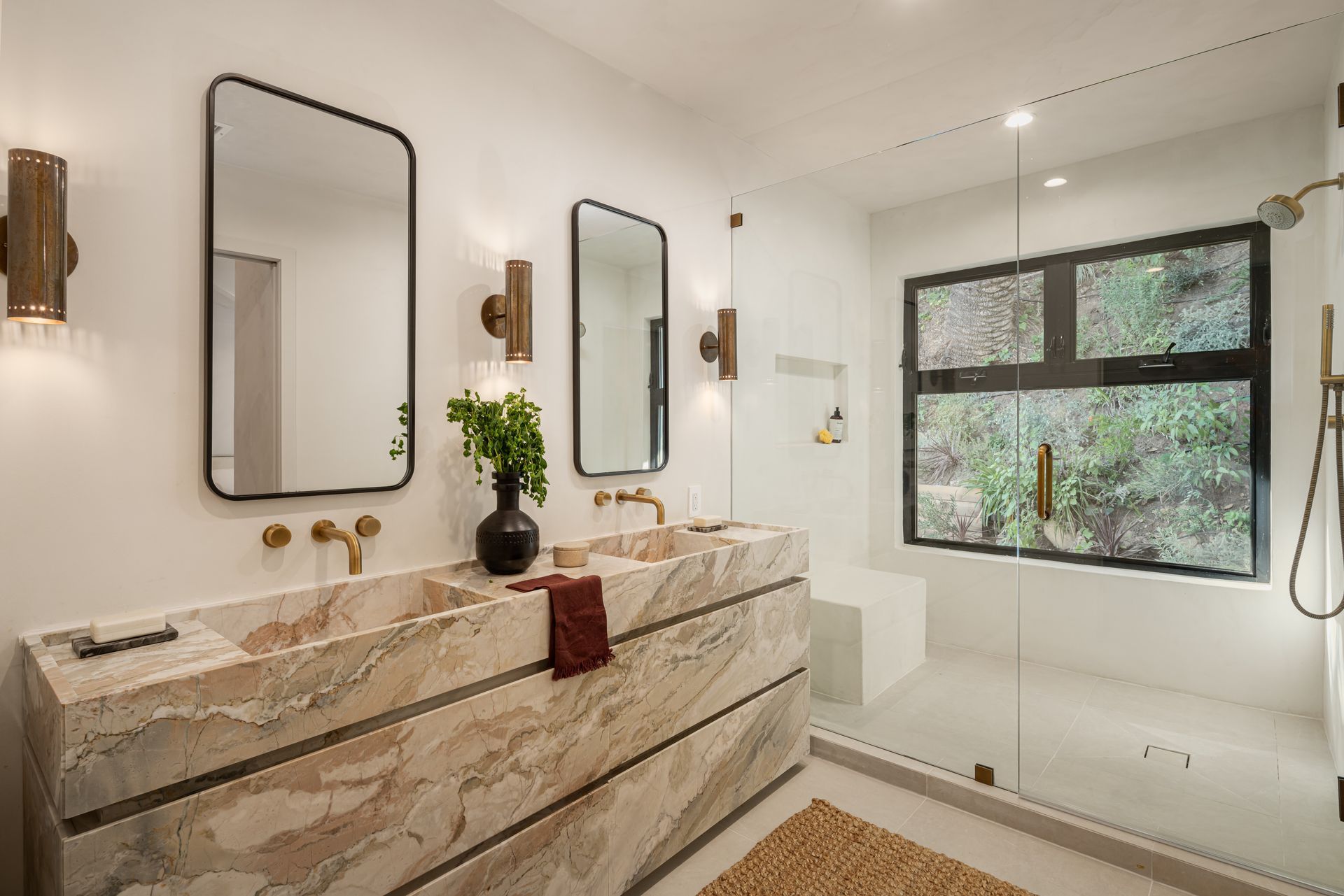 A bathroom with two sinks , two mirrors and a walk in shower.