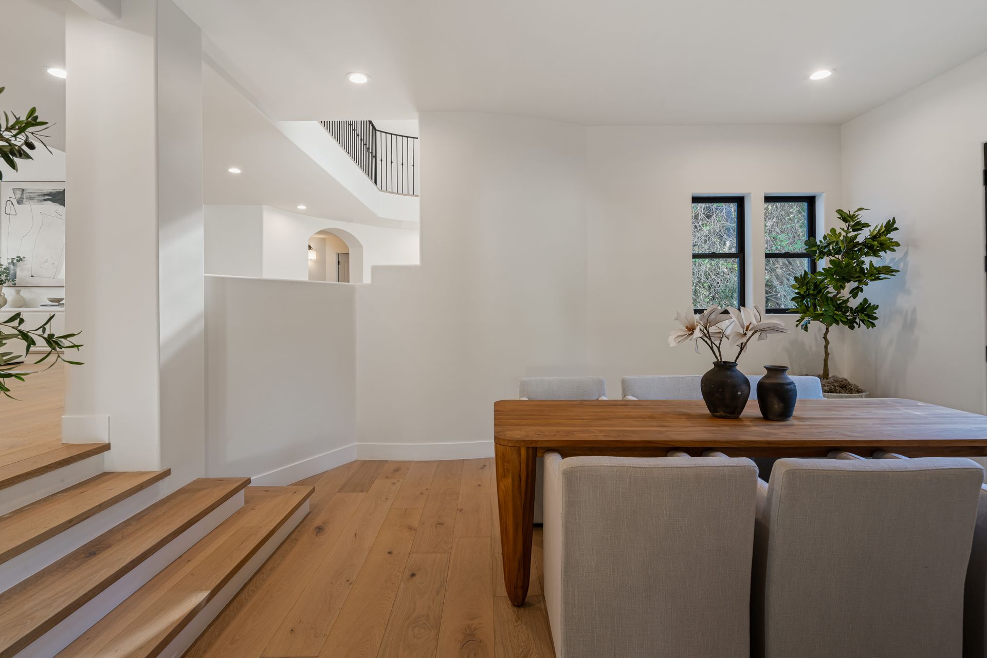 A dining room with a wooden table and chairs and stairs leading to the second floor.