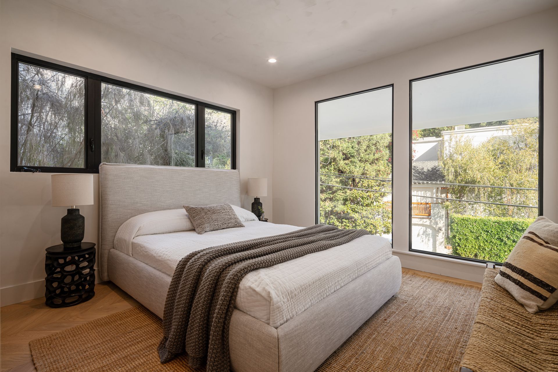 A bedroom with a bed , lamps , and lots of windows.