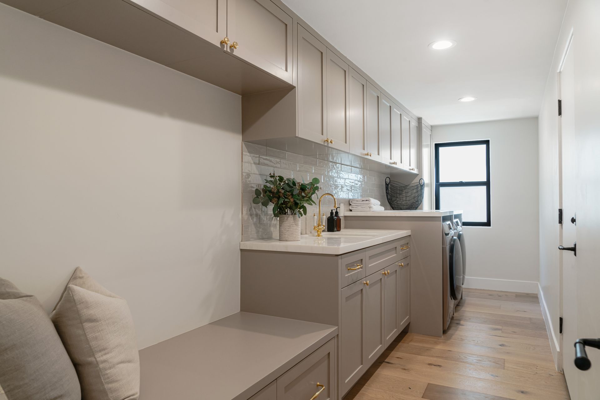 A laundry room with a bench and a washer and dryer.