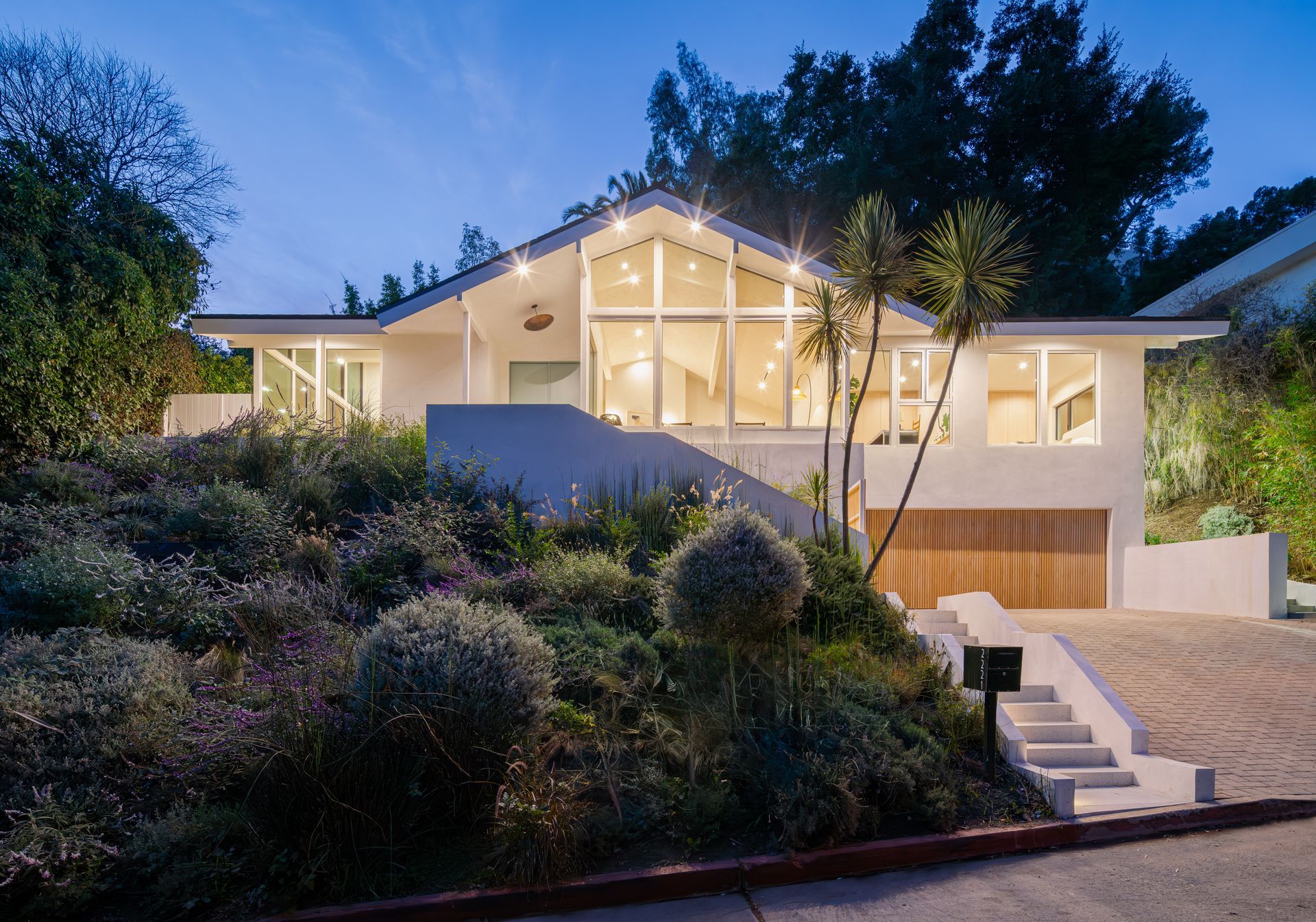 A white house with a lot of windows sits on top of a hill