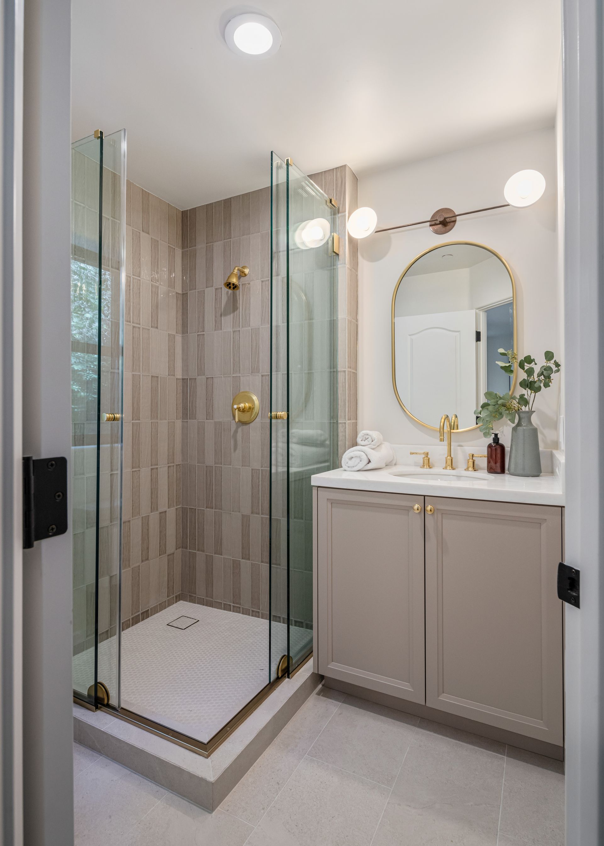 A bathroom with a walk in shower , sink and mirror.