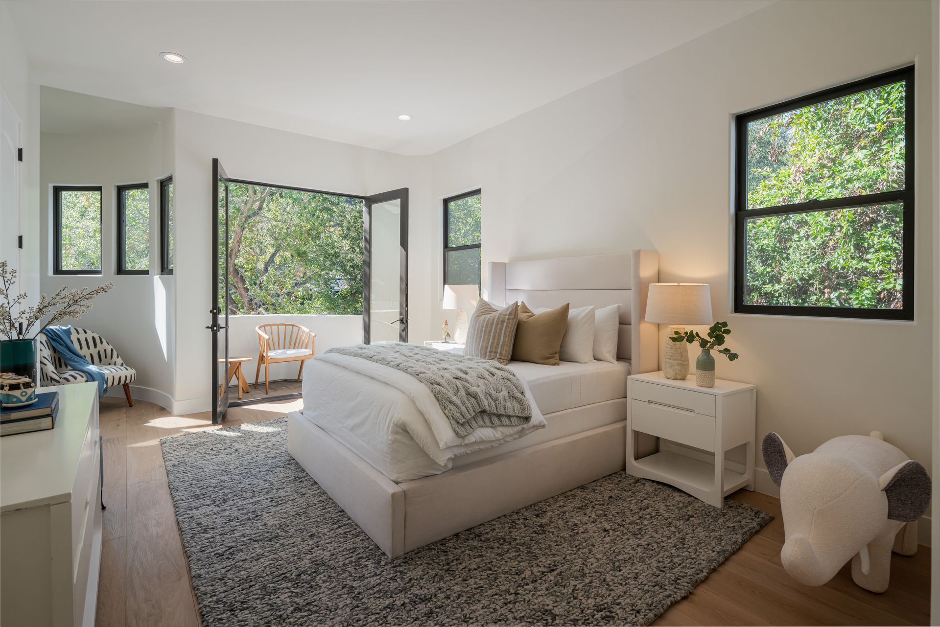 A bedroom with a bed , nightstand , rug and two windows.