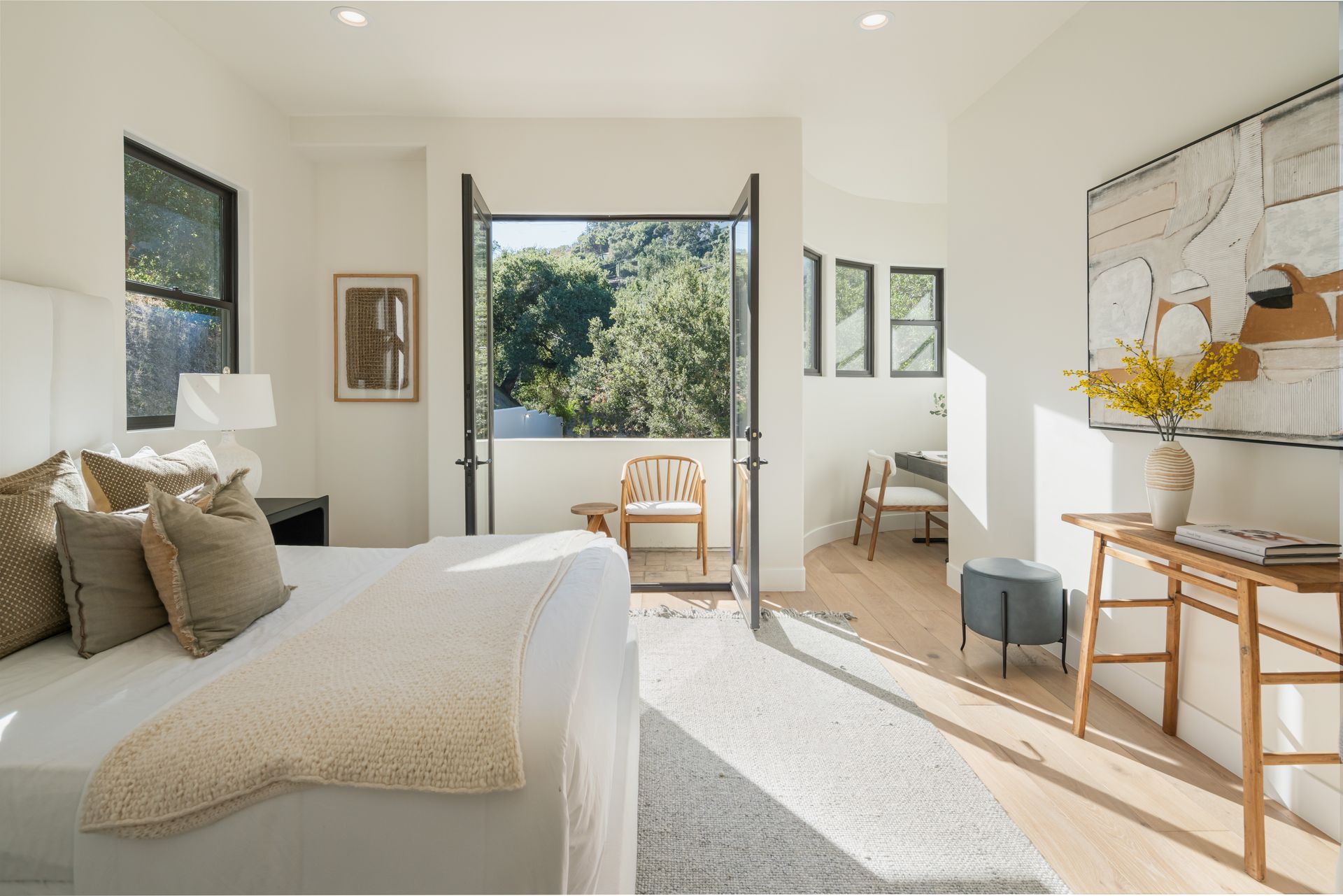 A bedroom with a bed , desk , chairs and a balcony.