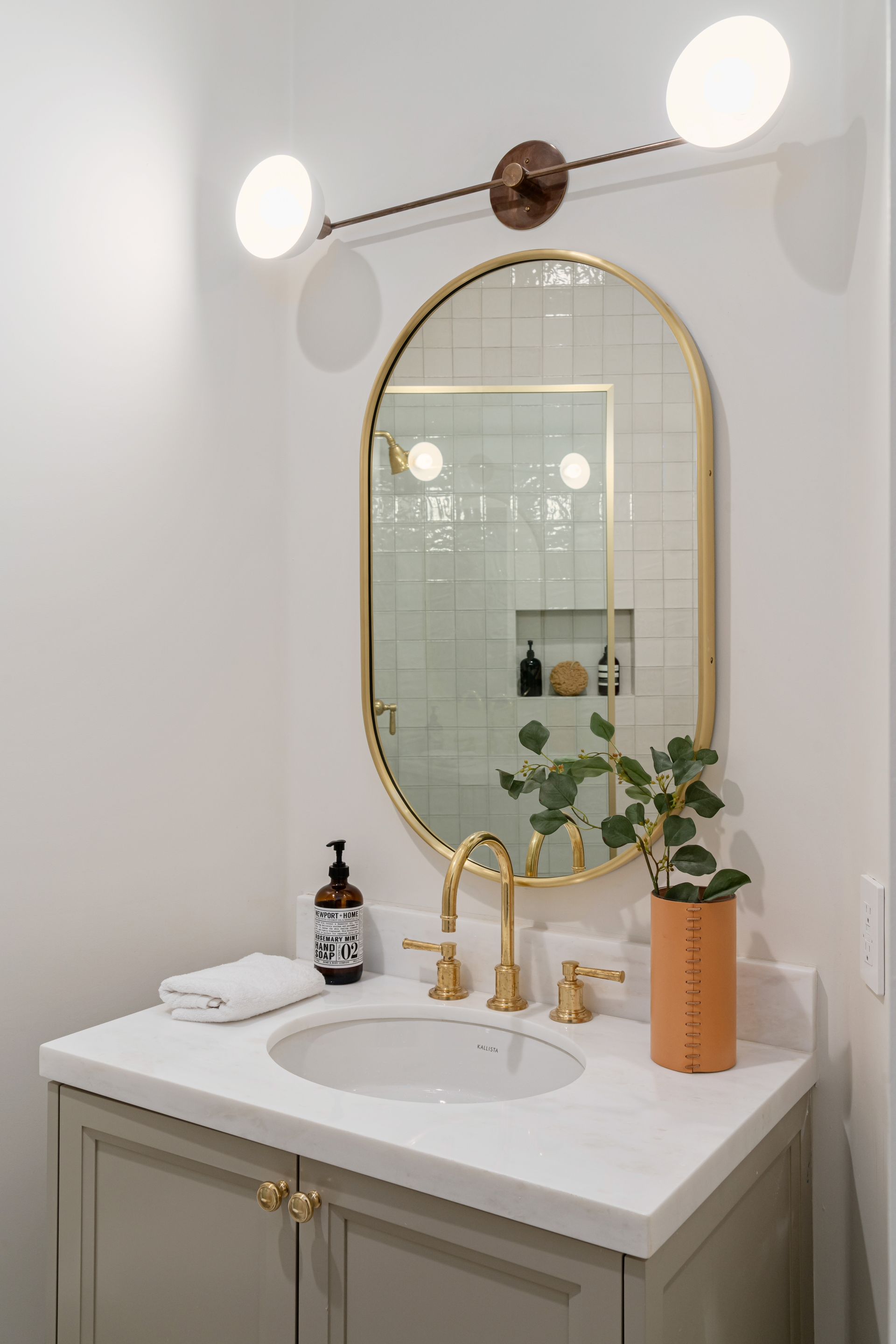 A bathroom with a sink , mirror and lights.