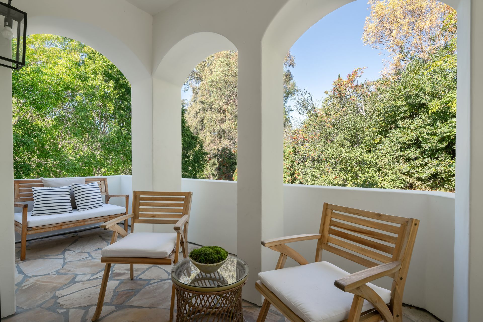 There are two chairs and a table on the porch.
