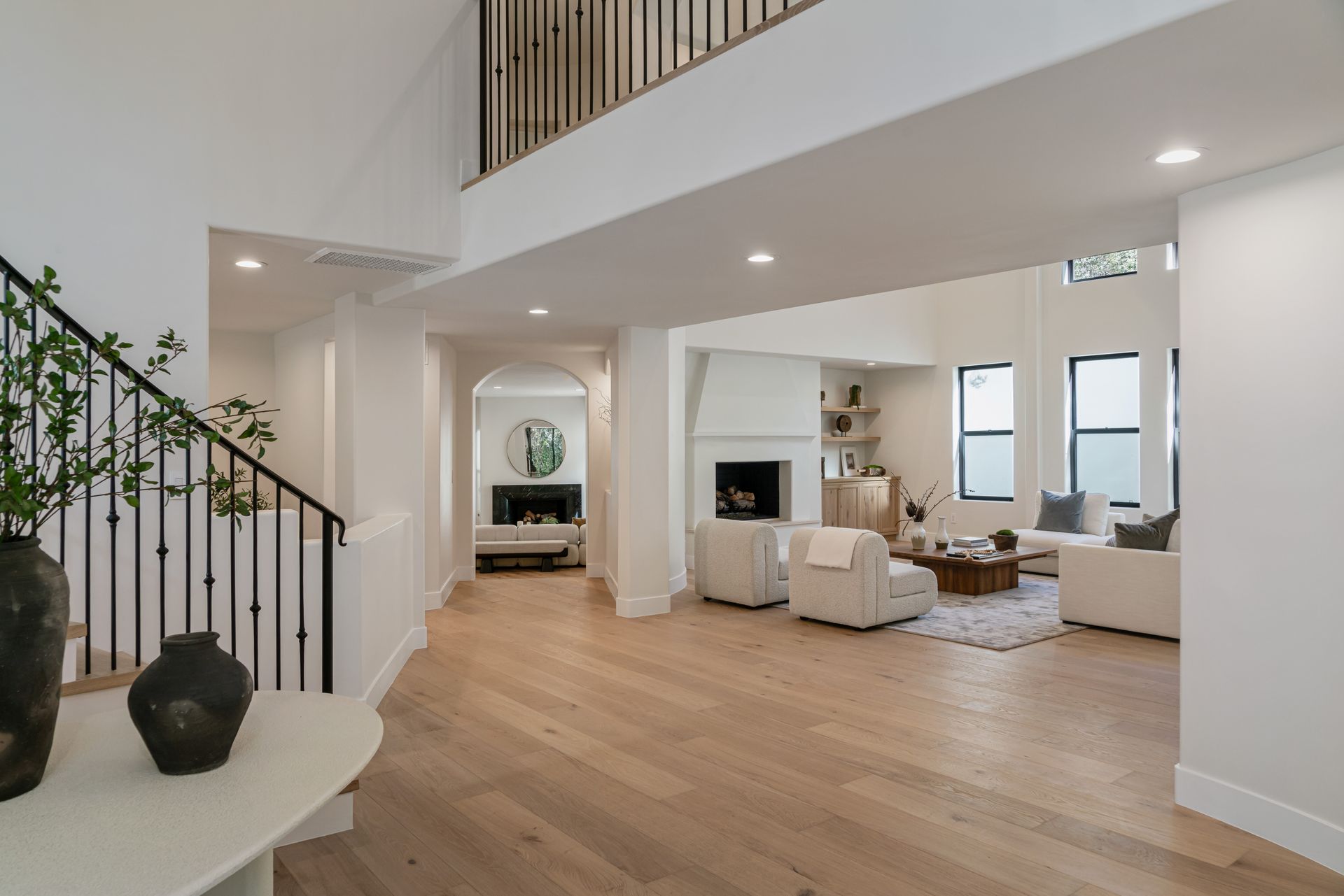 A living room with hardwood floors and a staircase leading to the second floor.