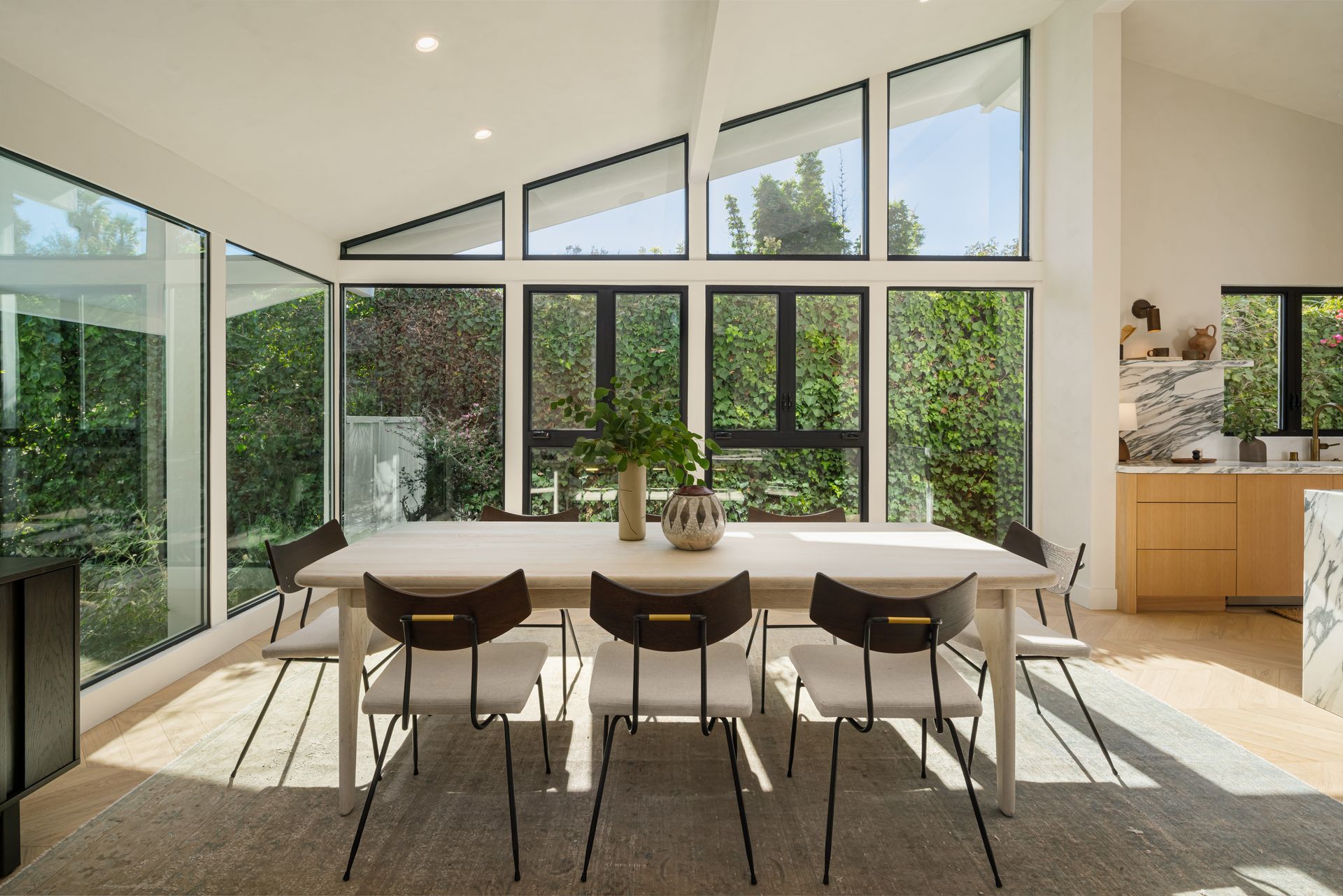 A dining room with a table and chairs and lots of windows
