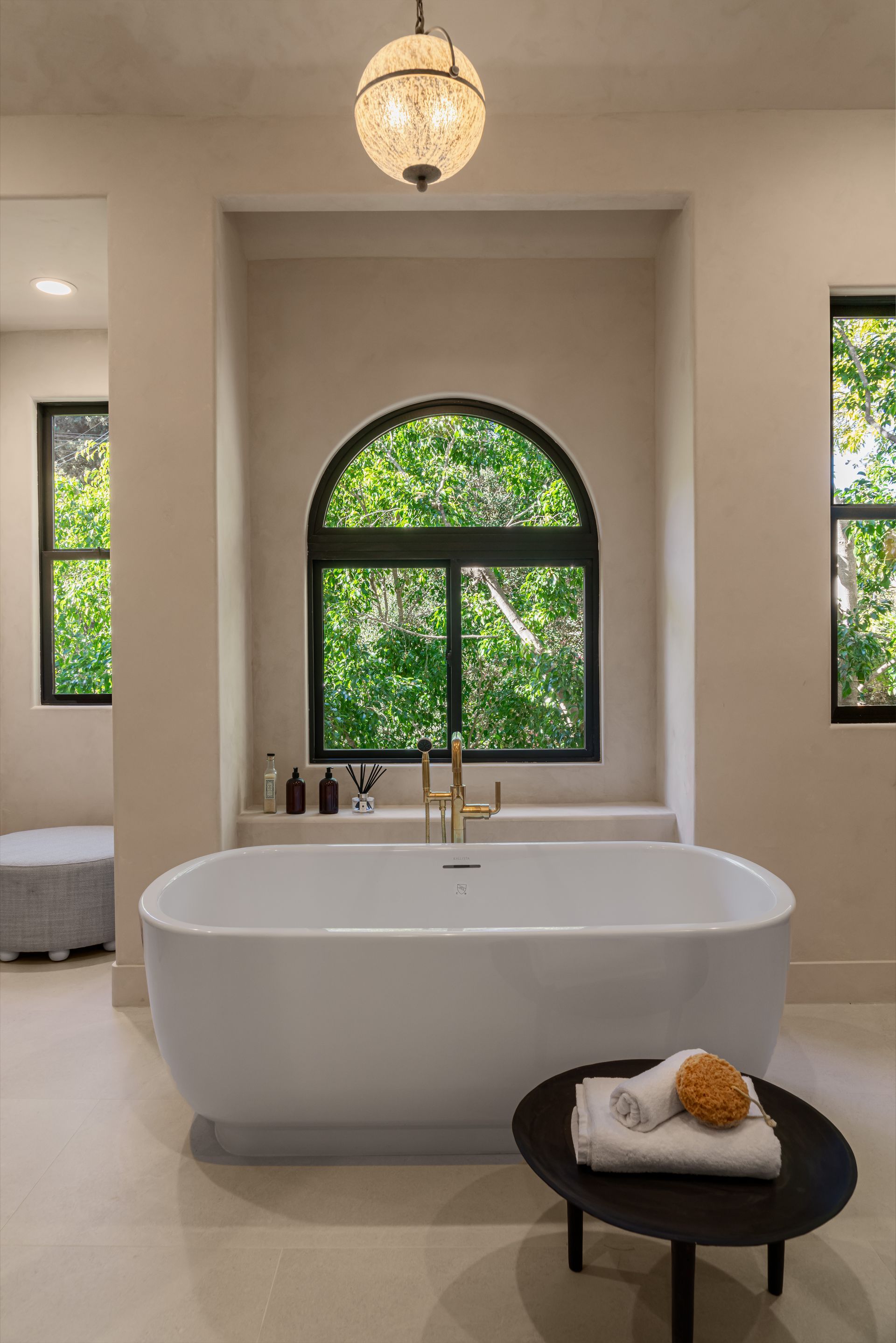 A bathroom with a bathtub and two windows.