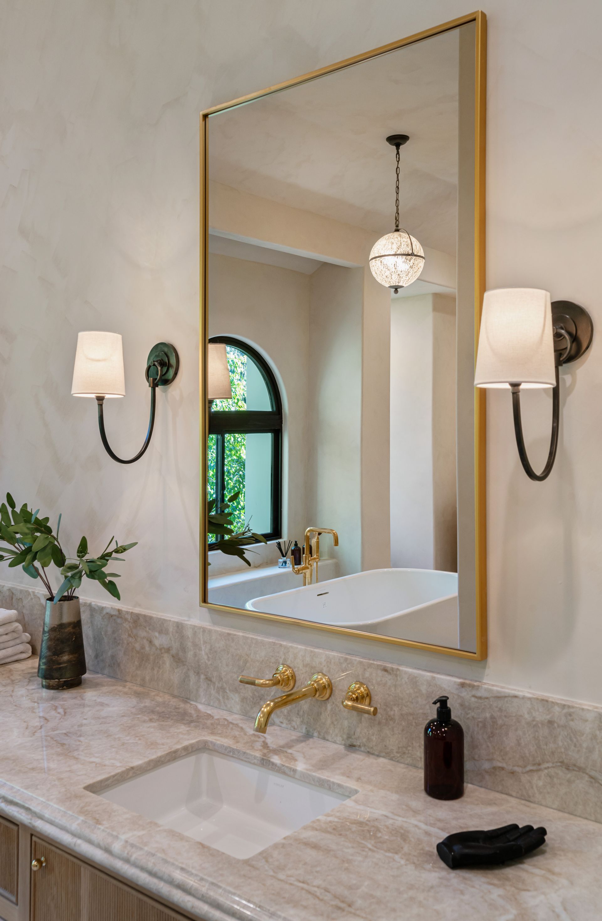 A bathroom with a sink , mirror and two lights.