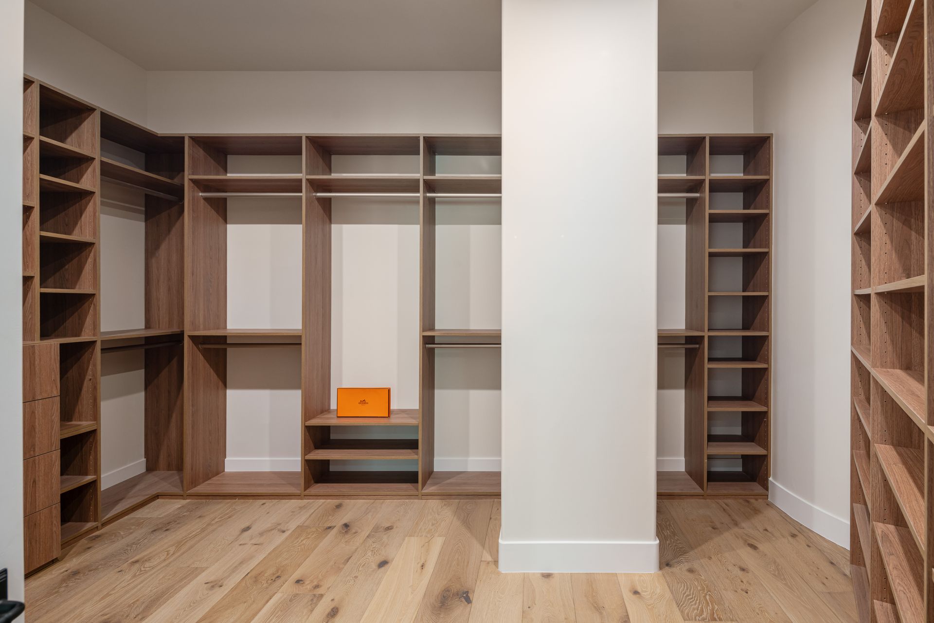 A walk in closet with wooden shelves and hardwood floors.