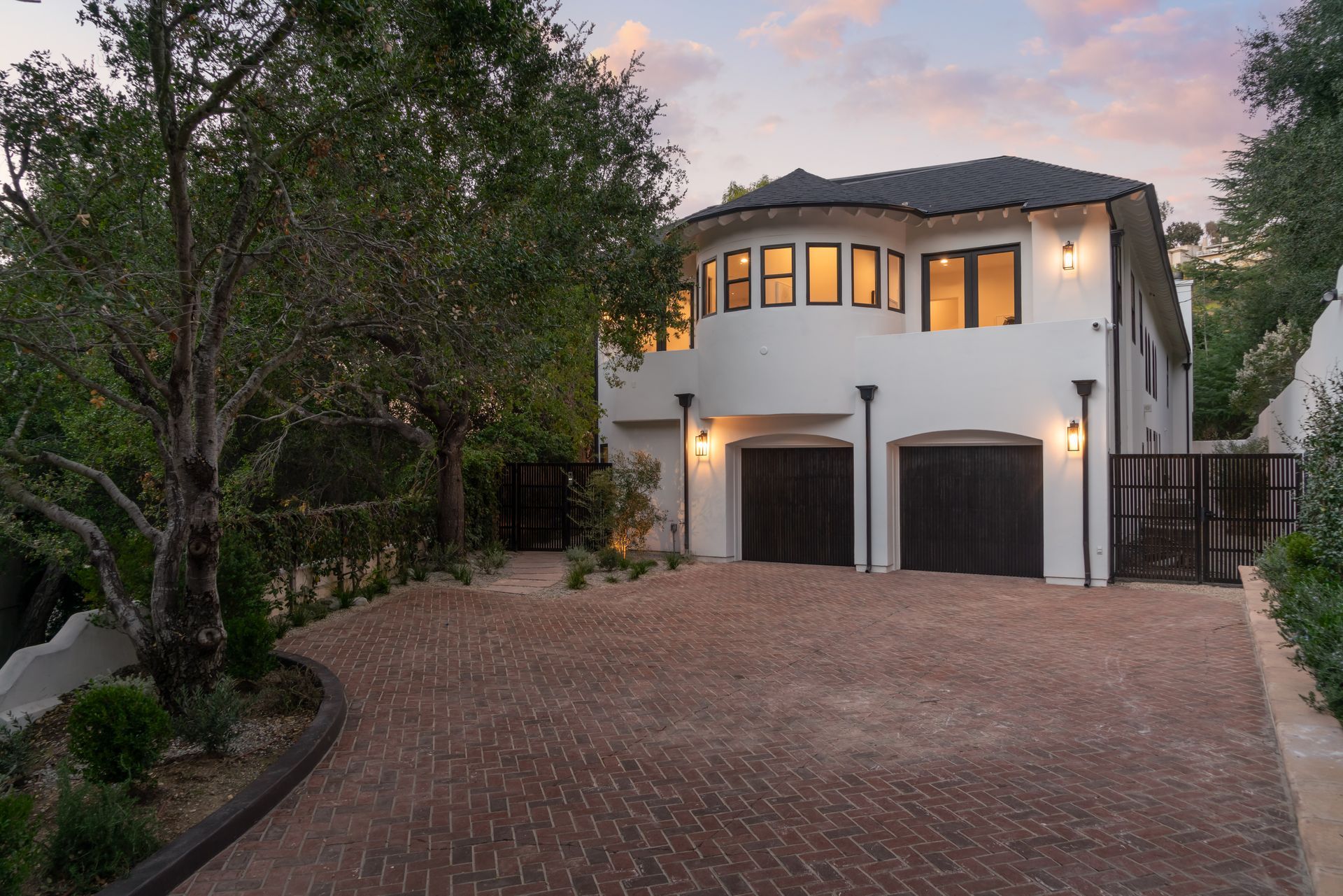 A large white house with two garages and a brick driveway
