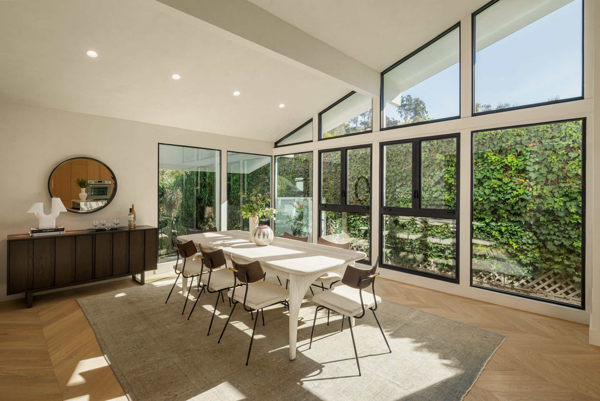 A dining room with a long table and chairs and lots of windows.