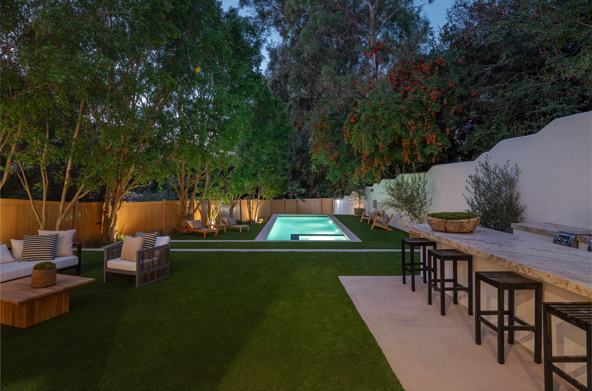 A large swimming pool is surrounded by a lush green lawn.