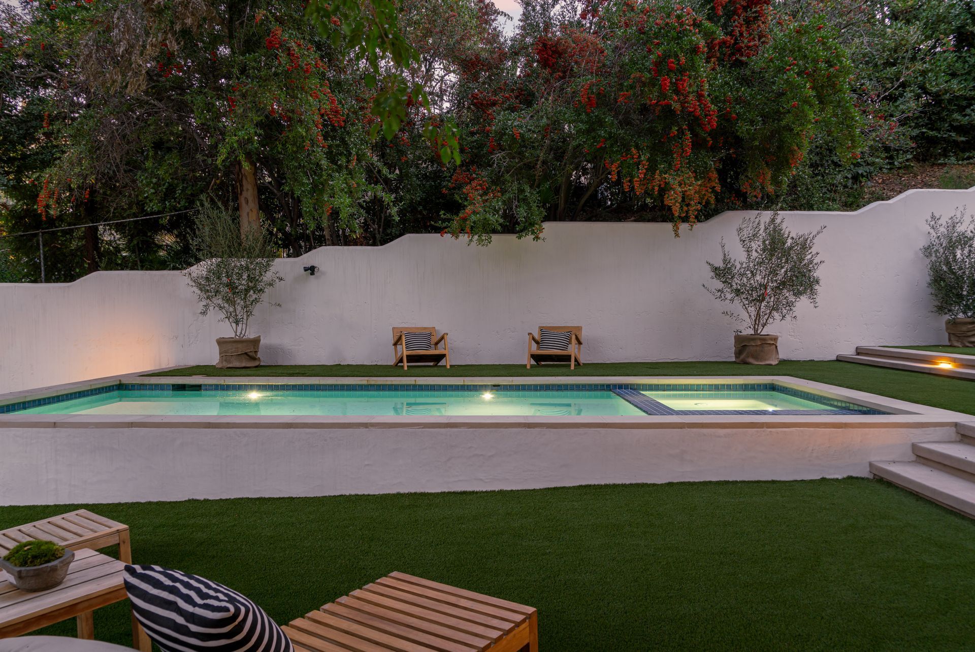 There is a large swimming pool in the backyard of a house.