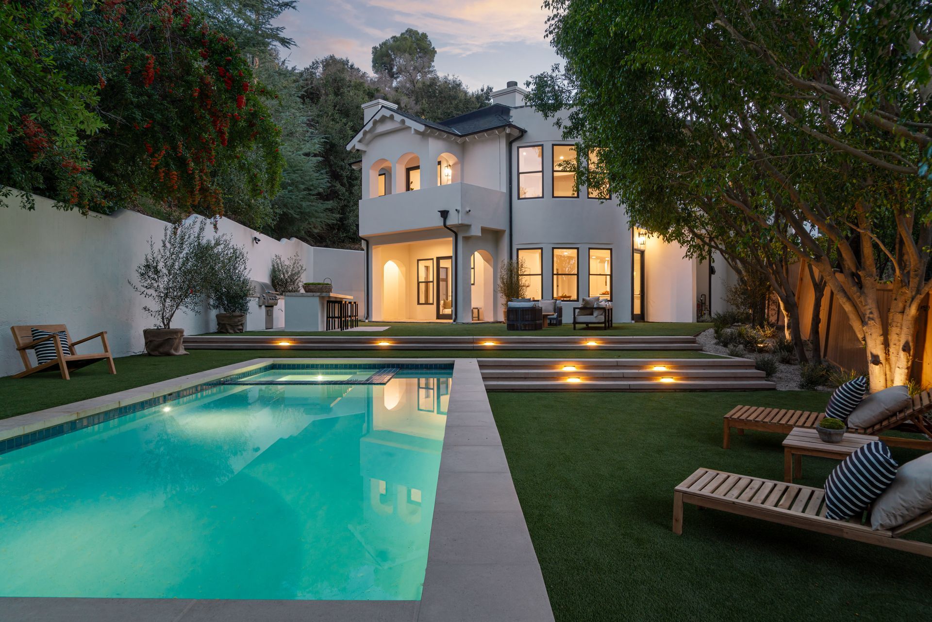 A large swimming pool is in the backyard of a house.