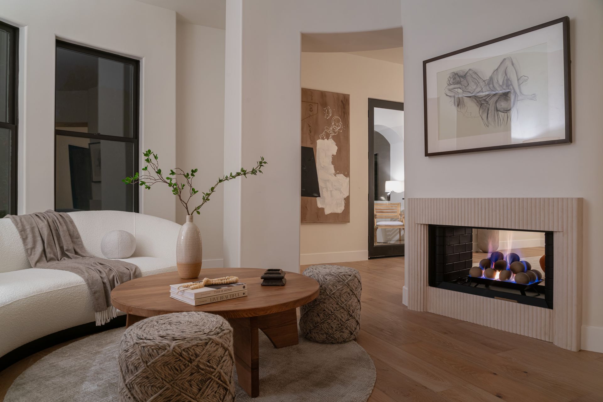 A living room with a fireplace , couch , coffee table and ottomans.
