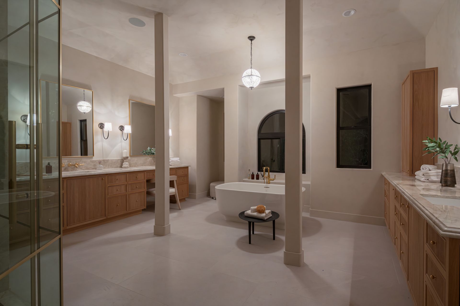 A bathroom with a tub , sinks , mirrors and columns.