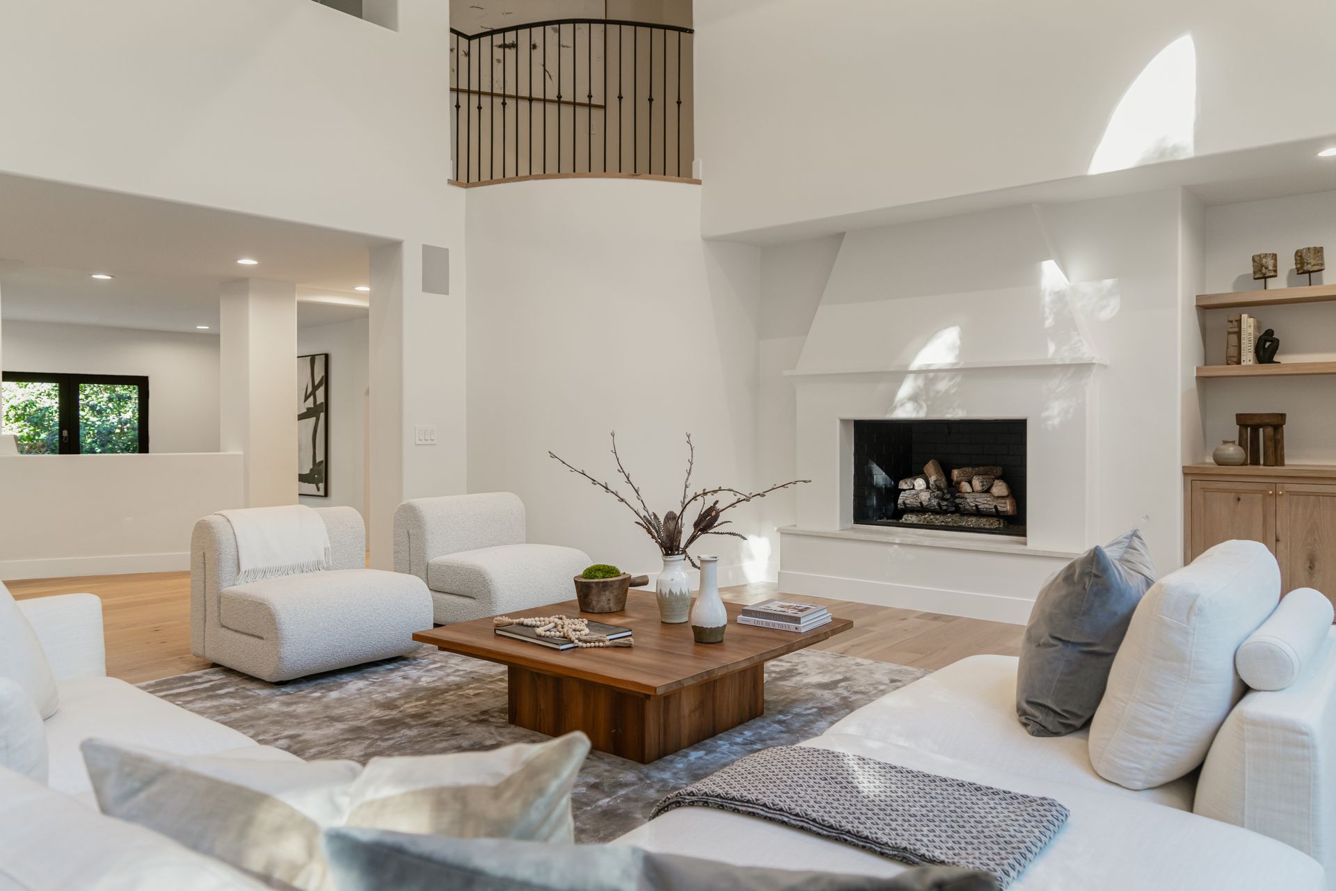 A living room with white furniture and a fireplace.