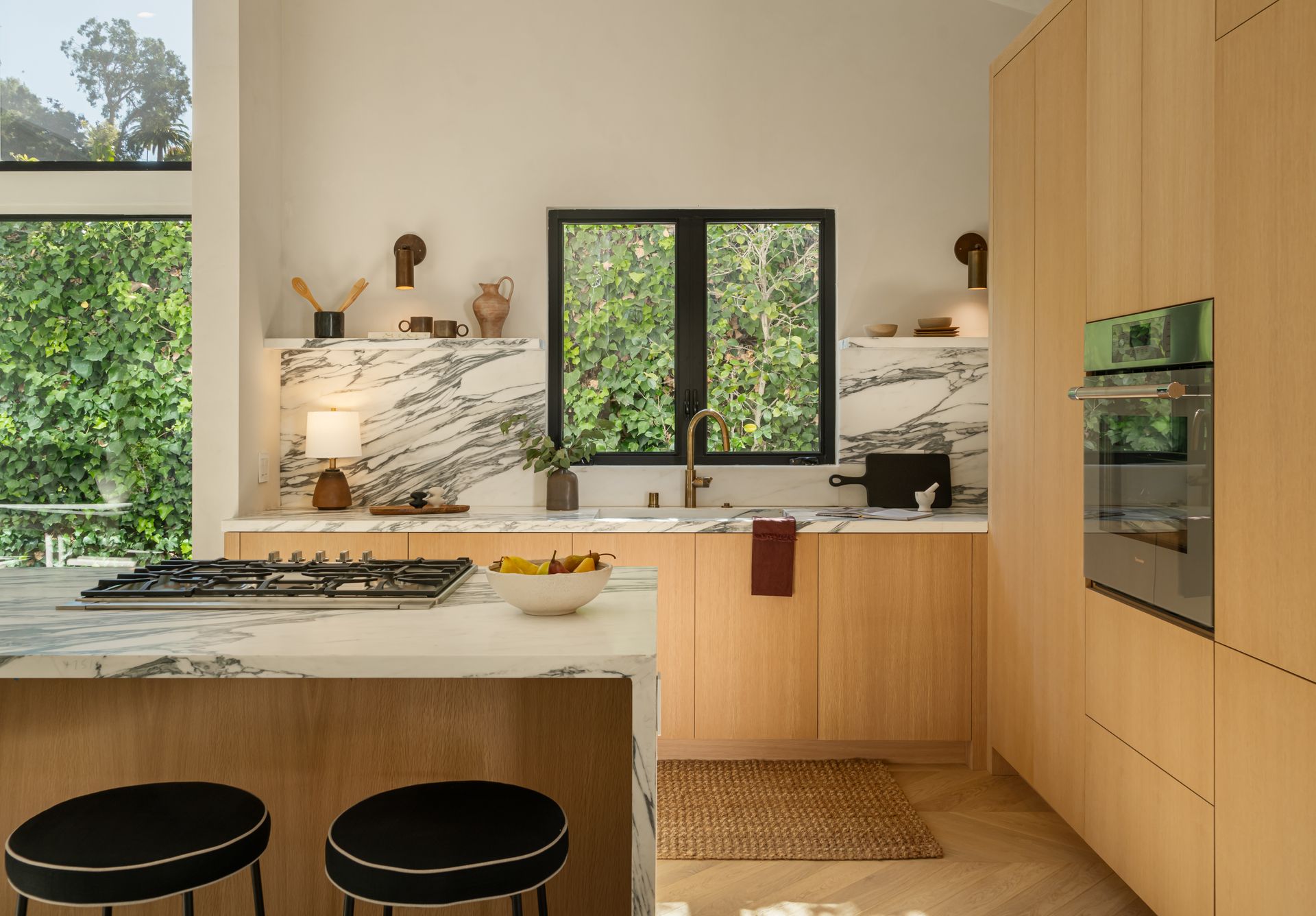 A kitchen with wooden cabinets , marble counter tops , a stove top oven , and a large island.