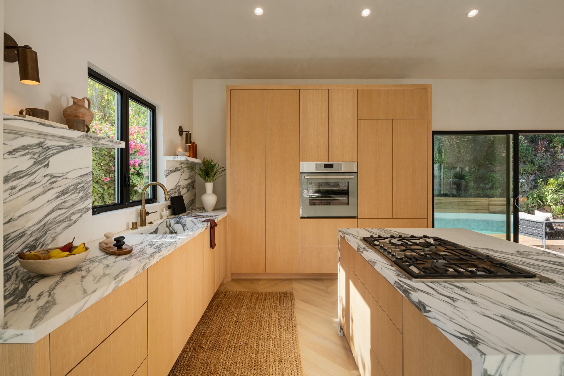 A kitchen with marble counter tops , wooden cabinets , and a stove top oven.