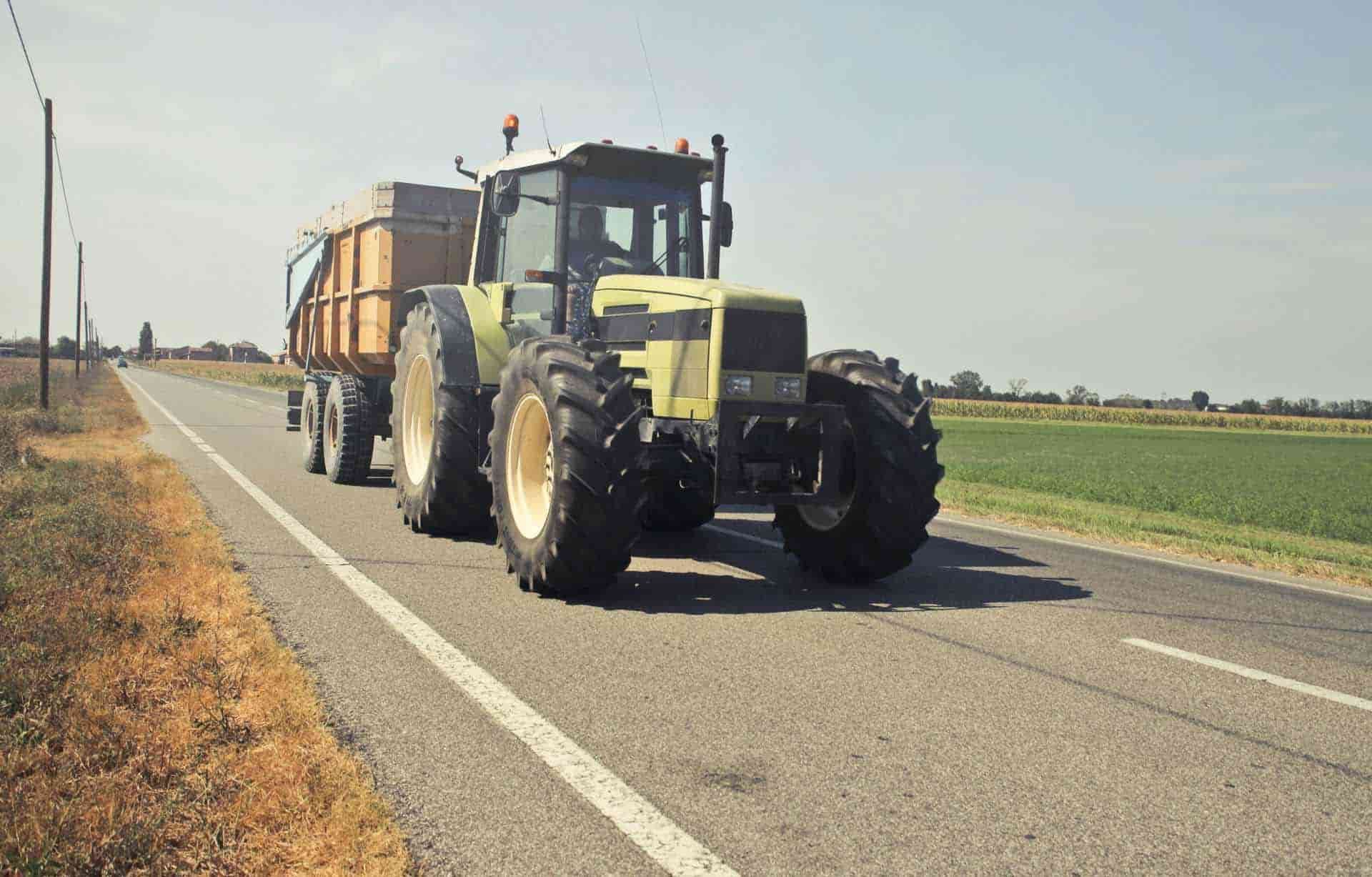 A Tractor Is Driving Down A Road With A Trailer Attached To It — Smitty's Tyres & More In Taminda, NSW