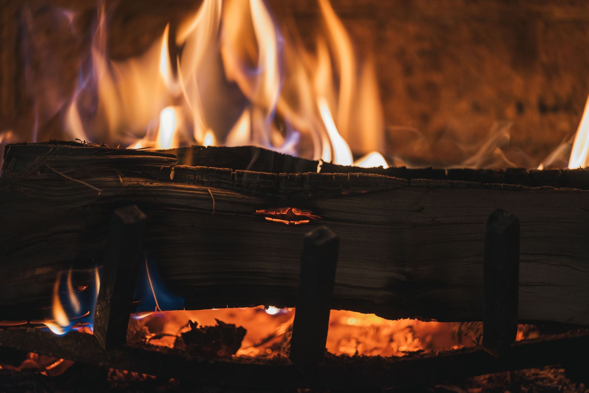 A crackling fireplace with orange flames burning behind dark logs and glowing embers