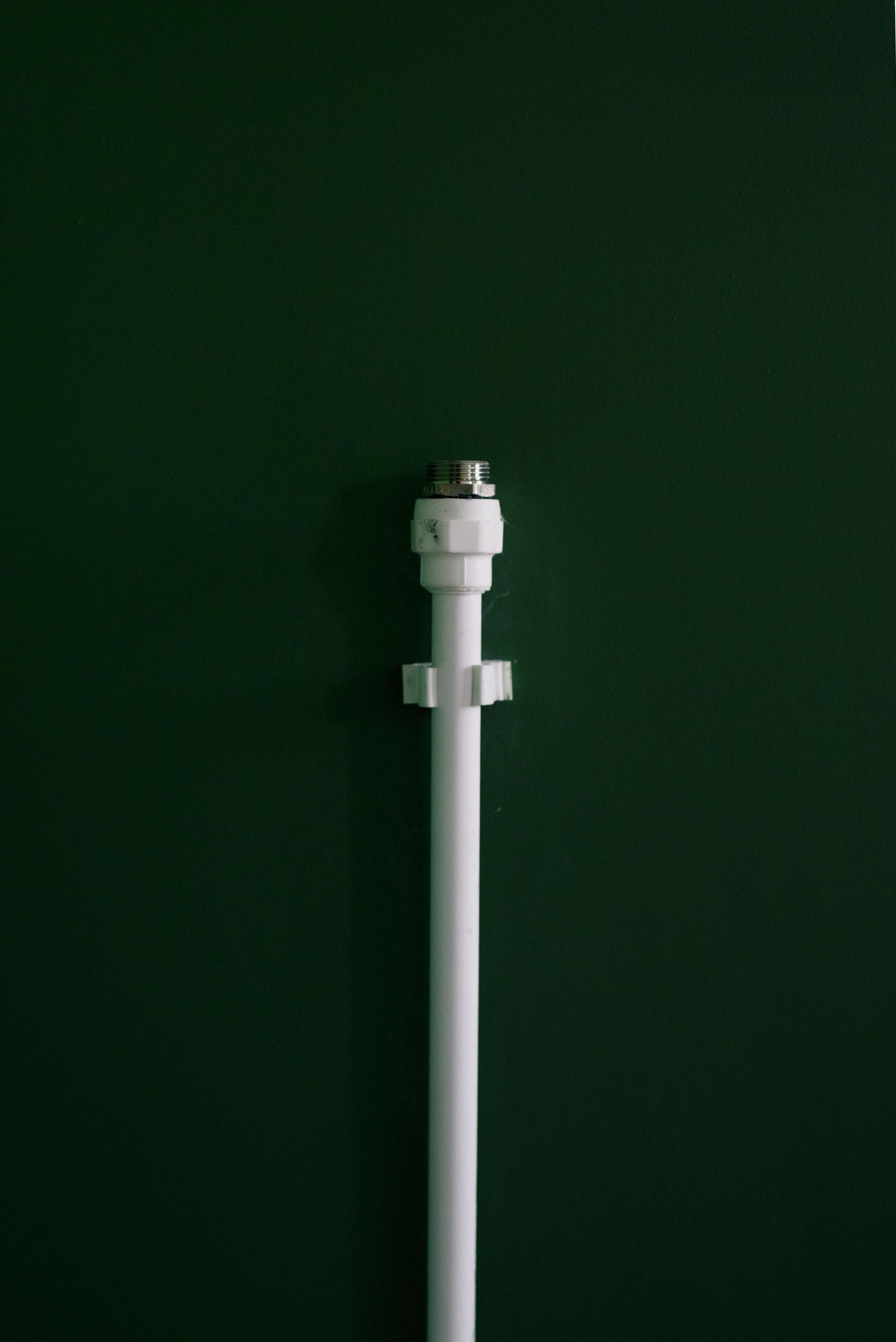 Weathered wall with exposed copper and white PVC pipes in an industrial setting
